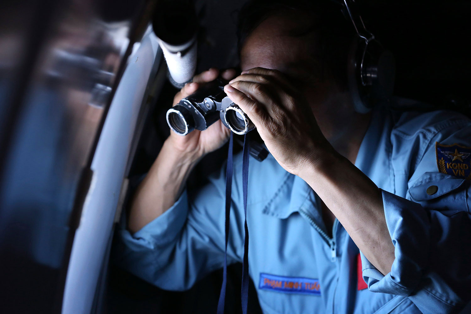 Vietnamese Air Force Col. Pham Minh Tuan uses binoculars on board an aircraft during a mission to search for the missing Malaysia Airlines Flight 370 in the Gulf of Thailand, on March 13, 2014. (AP)