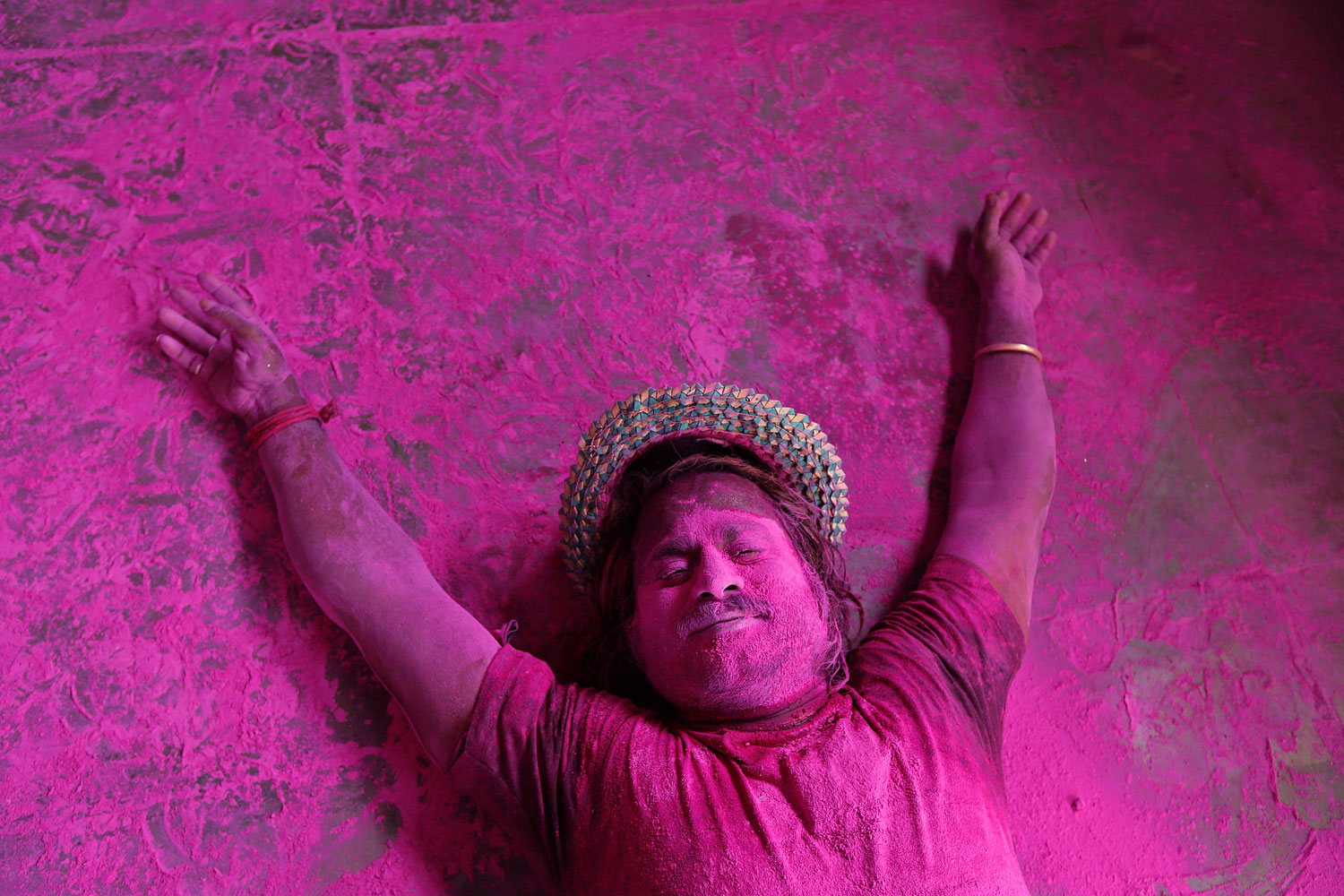 A man lies on the ground smeared with colored powder during celebrations marking Holi, the Hindu festival of colors, in Allahabad, India, March 17, 2014.