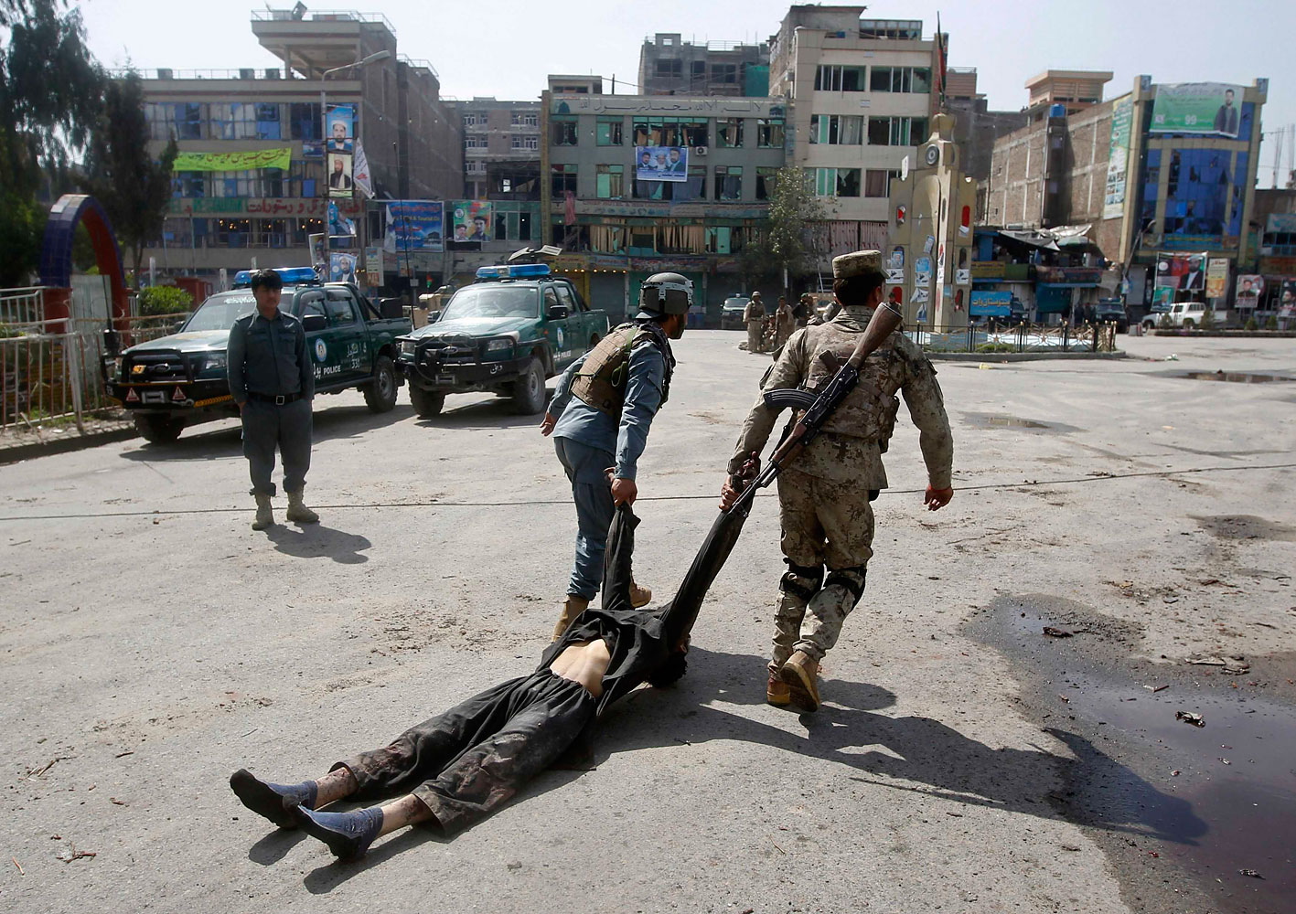 Afghan policemen remove the dead body of a Taliban insurgent from the site of a suicide car bomb attack in Jalalabad province, March 20, 2014. (Parwiz—Reuters)