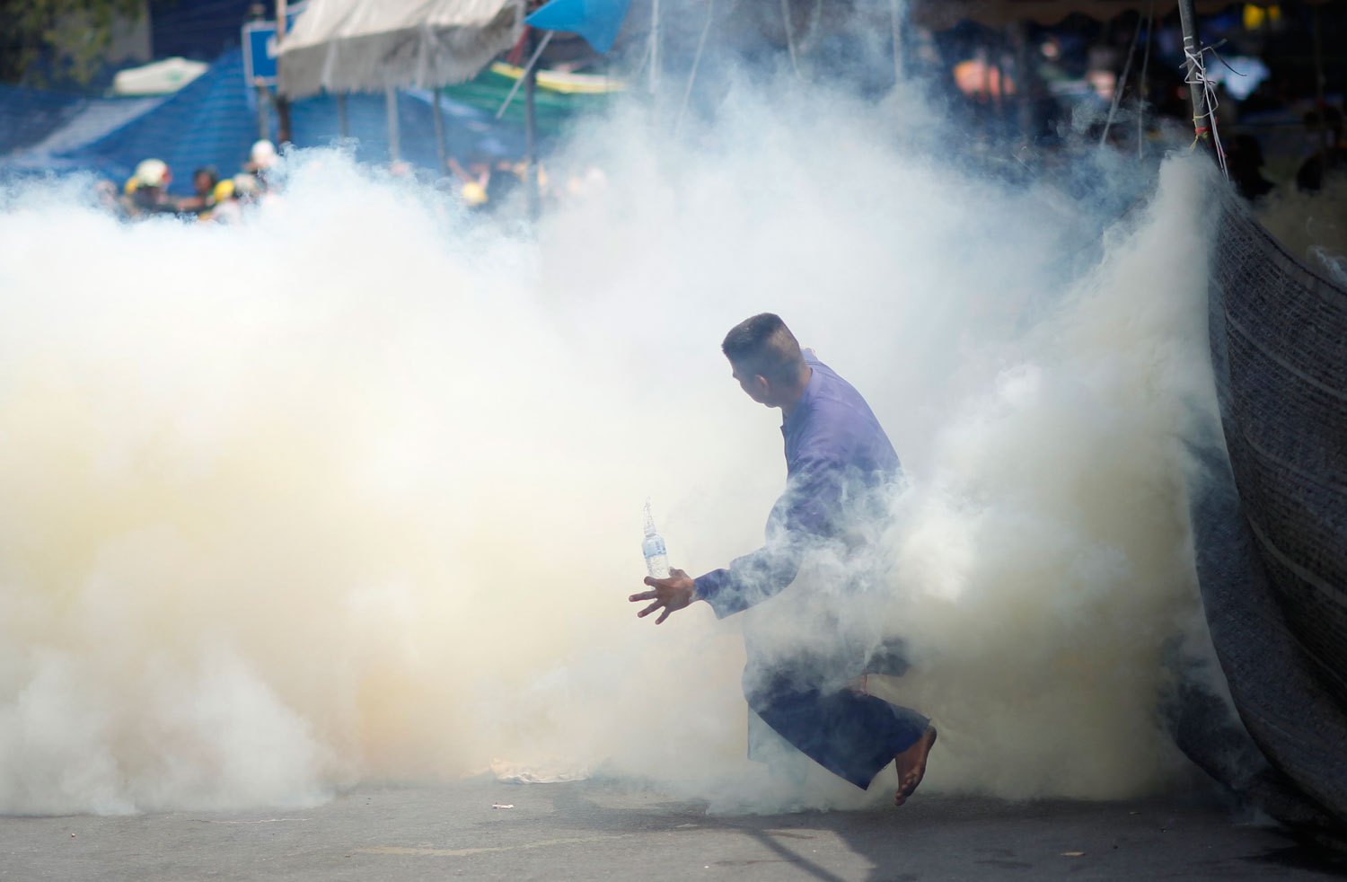 An anti-government protester is caught in tear gas during clashes with riot police in Bangkok, on Feb. 18, 2014.