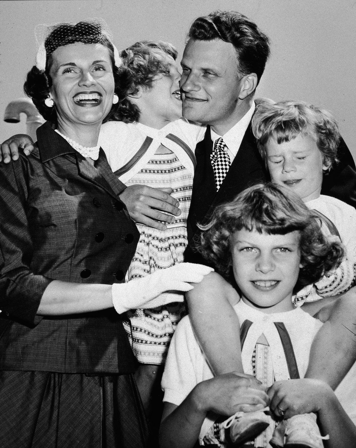 After returning from his 'Crusade for Christ' tour, Graham embraces his wife, Ruth, and his children in New York.