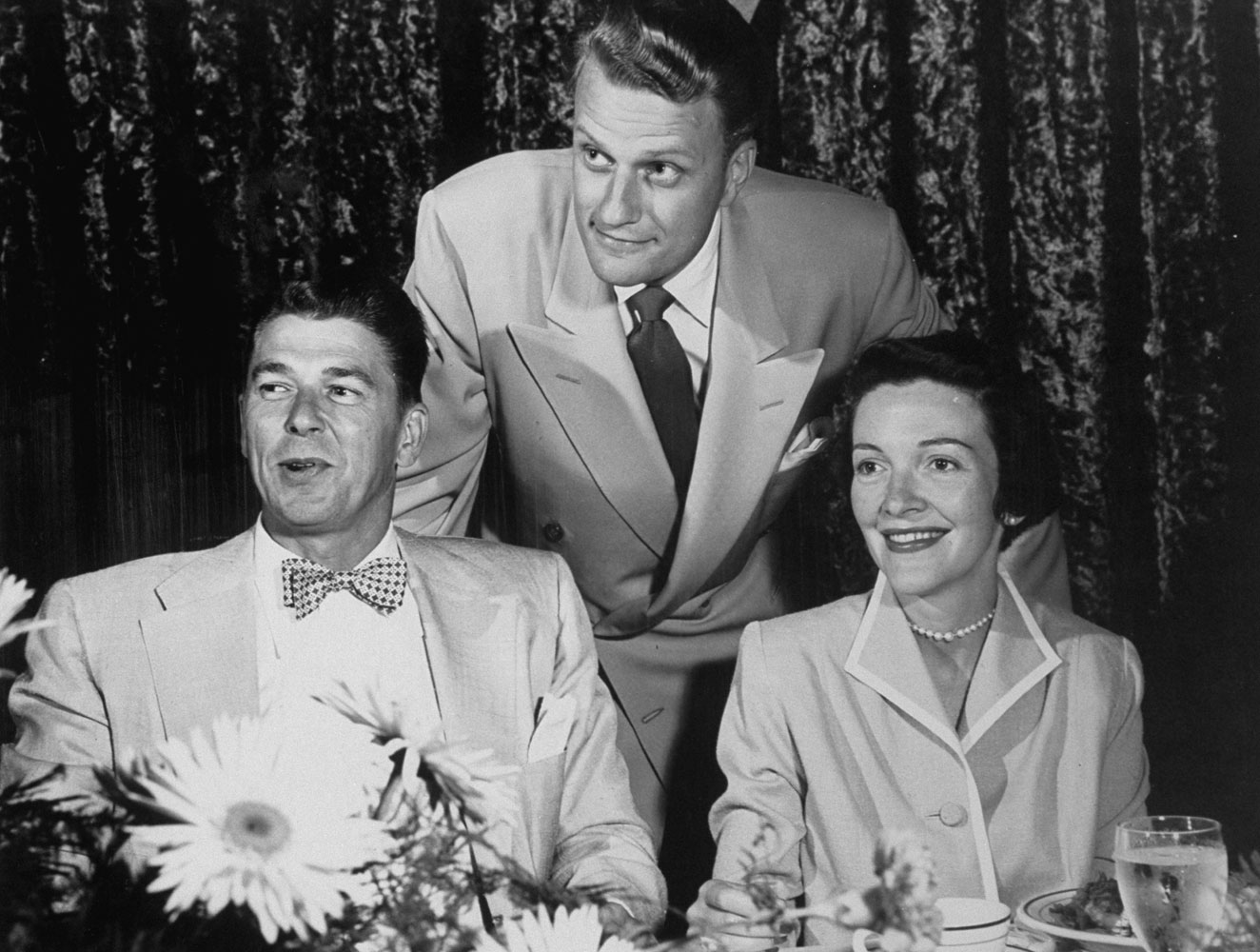 Husband and wife actors Ronald Reagan and Nancy Davis mug with Graham at a movie exhibitors' meeting in Dallas, 1952. The friendship between Graham and Reagan lasted through his presidency.