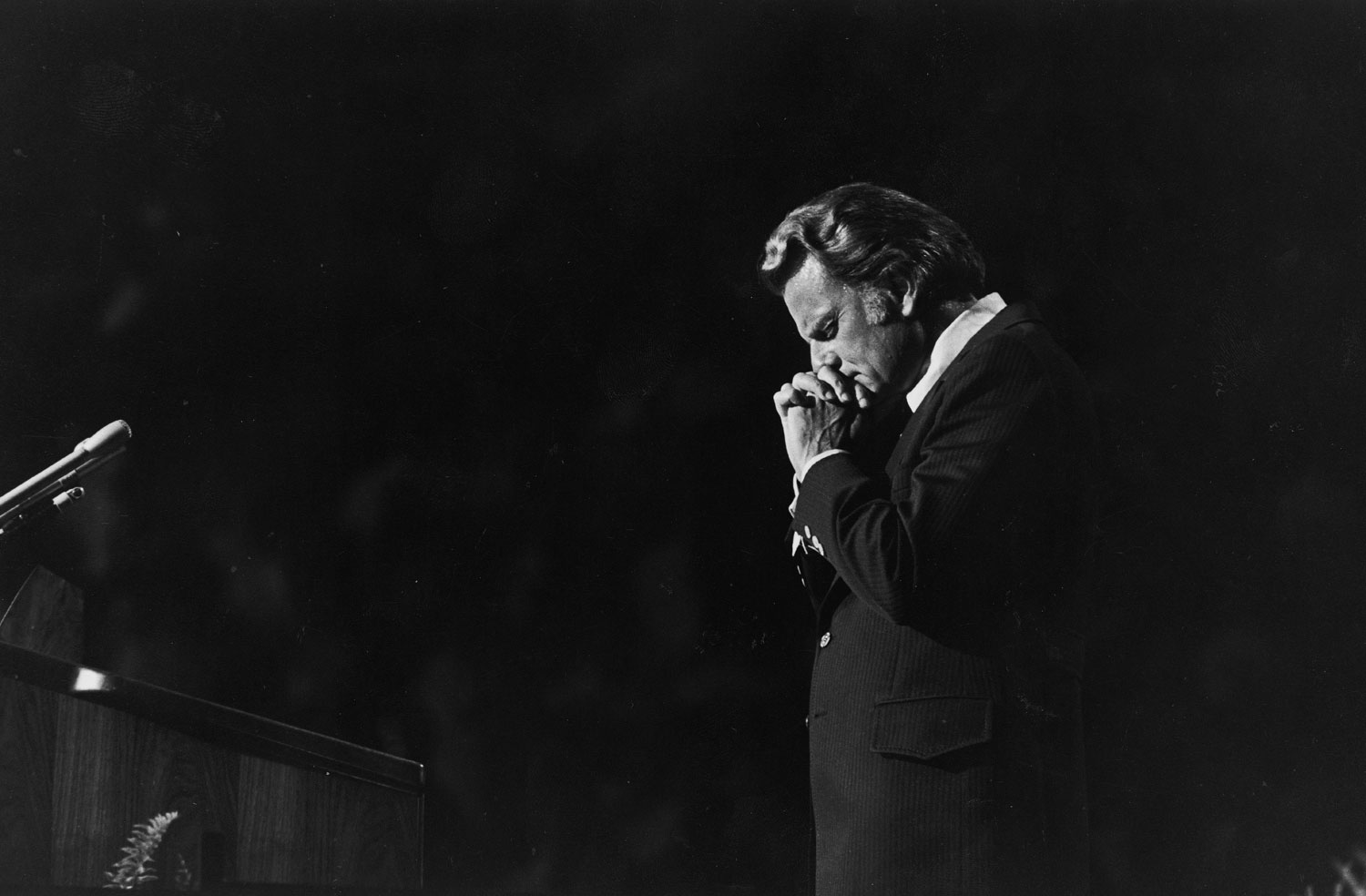 Graham prays during a crusade in Charlotte, 1972.