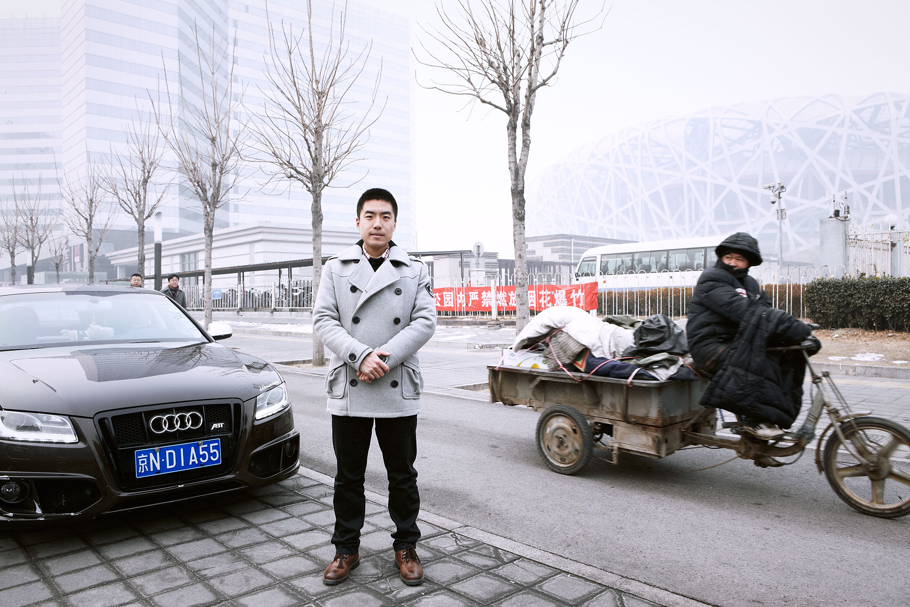 Zhao Xiadi next to his Audi A5 with National Stadium in the background. Beijing, China, Chaoyang District. February 15, 2014
