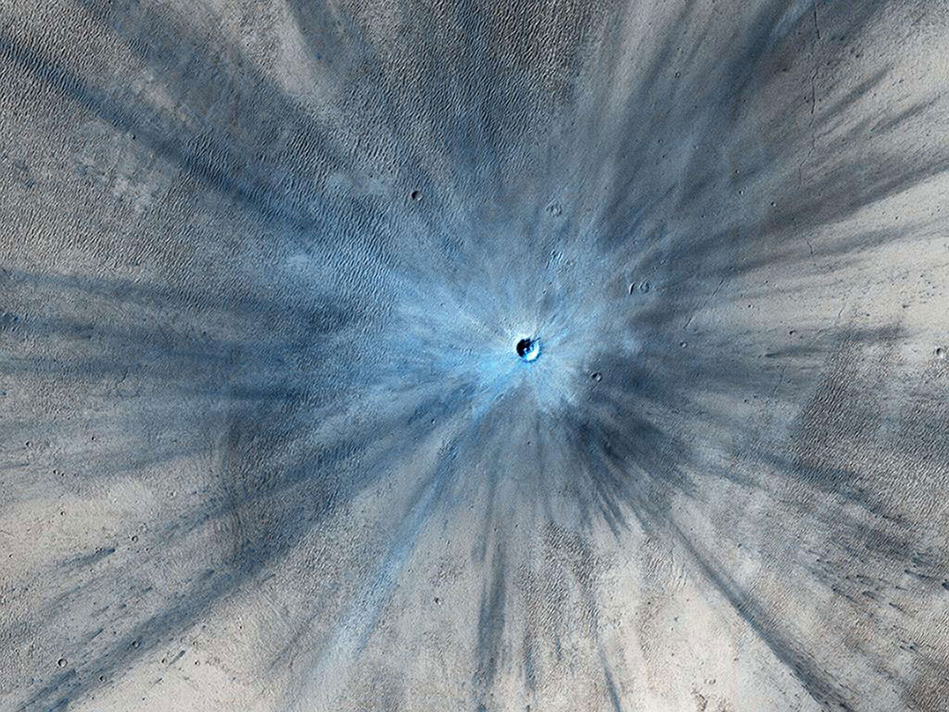A fresh impact crater, captured by NASA's Mars Reconnaissance Orbiter on Nov. 19, 2013 and released on Feb. 5, 2014. The crater spans approximately 100 feet (30 meters) in diameter and is surrounded by a large, rayed blast zone.