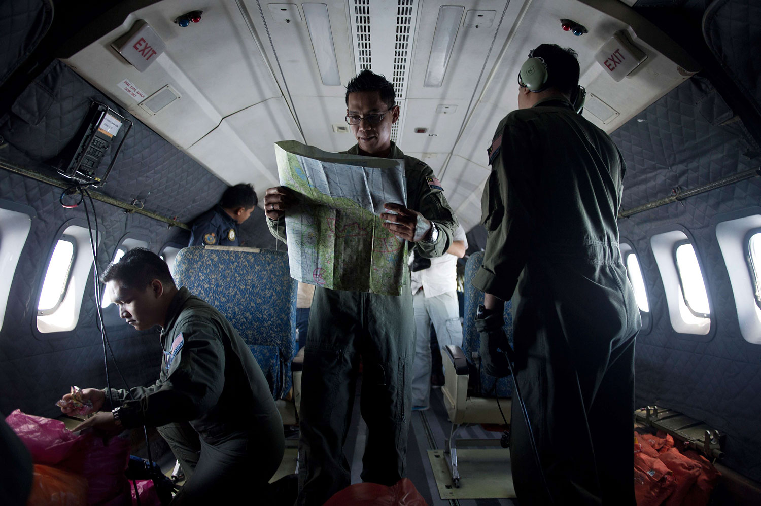 A Royal Malaysian Air Force Navigator captain, Izam Fareq Hassan, center, looks at a map onboard a Malaysian Air Force CN235 aircraft during a search and rescue (SAR) operation to find the missing Malaysia Airlines flight MH370 plane over the Strait of Malacca on March 14, 2014. (Mohd Rasfan—AFP/Getty Images)