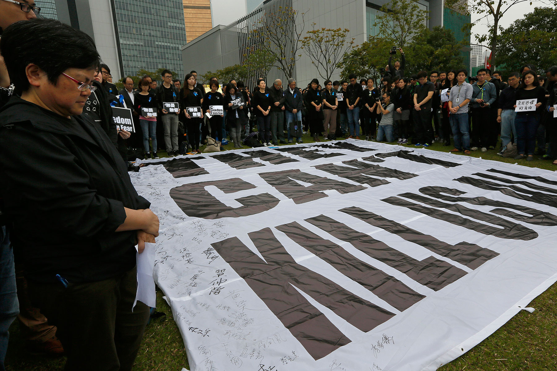 Journalists and their supporters stand in a five minutes silent around a huge banner reads " They can't kill us all " during a rally outside the government headquarter in Hong Kong, March 2, 2014 (Vincent Yu—AP)