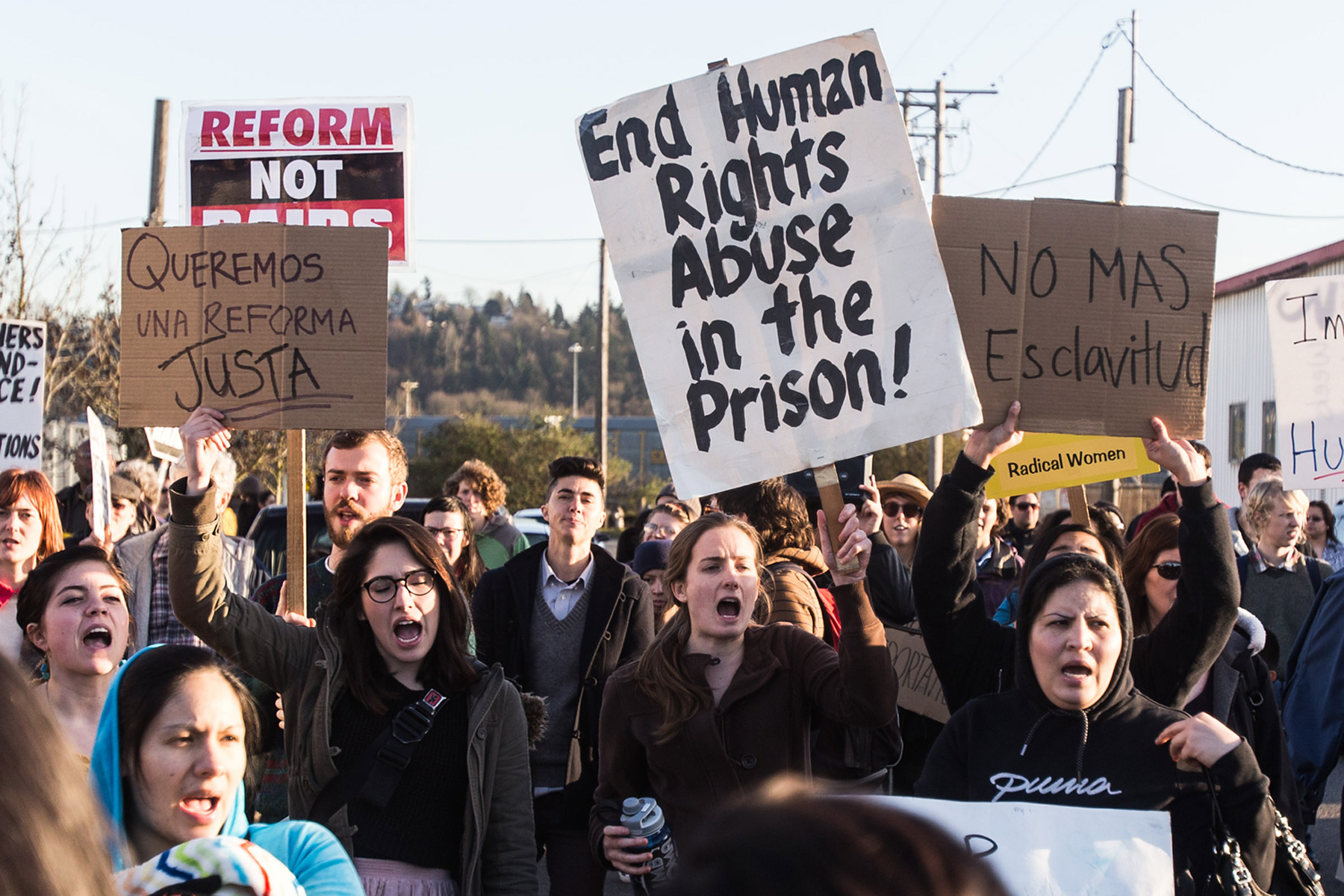 Demonstrators opposing deportations hold up signs while chanting in English and Spanish outside of the Northwest Detention Center in Tacoma, Wa. on March 11, 2014. (Thomas Soerenes—The News Tribune/AP)