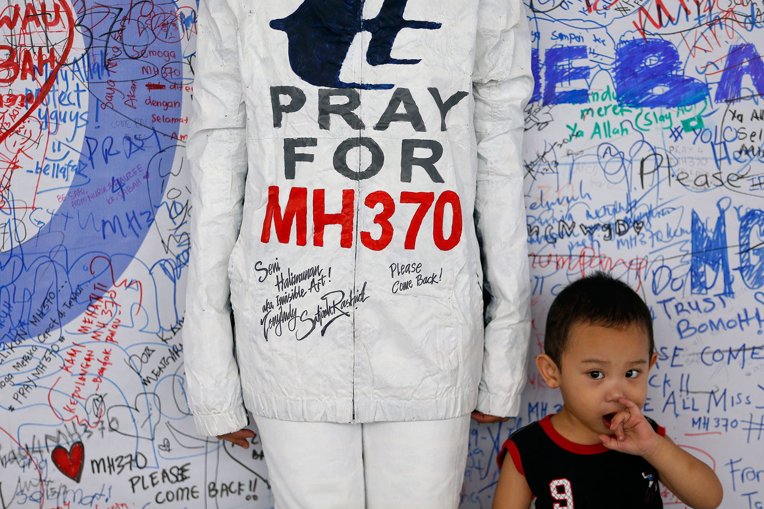 A boy stands beside a model posing for pictures during an art performance in support for the passengers of the missing Malaysia Airlines MH370 at the departure hall of the Kuala Lumpur International Airport March 17, 2014. (Damir Sagolj—Reuters)