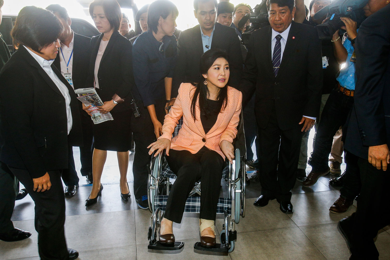 Thailand's Prime Minister Yingluck Shinawatra, center, arrives on a wheelchair at the Royal Police Cadet Academy in Nakorn Pathom province, March 18, 2014. (Athit Perawongmetha—Reuters)