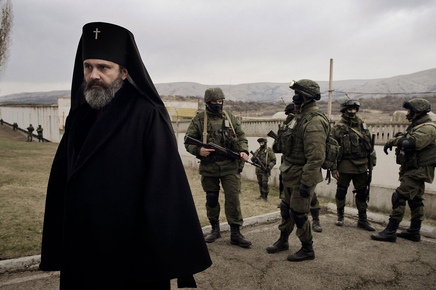 A priest stands next to troops in Perevalnoye on Sunday.