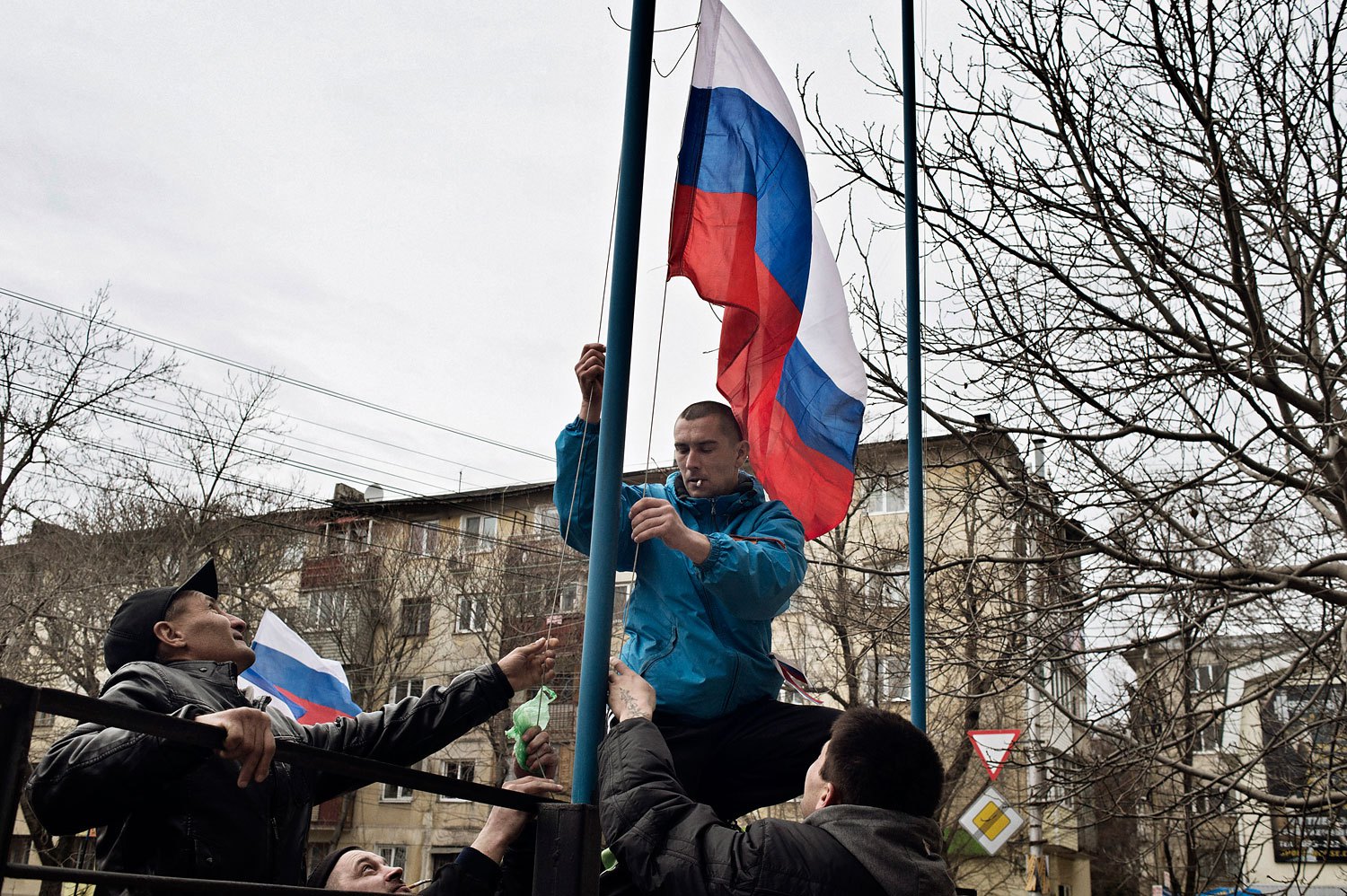 Members of a pro- Russian group raise a Russian flag in front of a military base in Simferopol on Sunday.