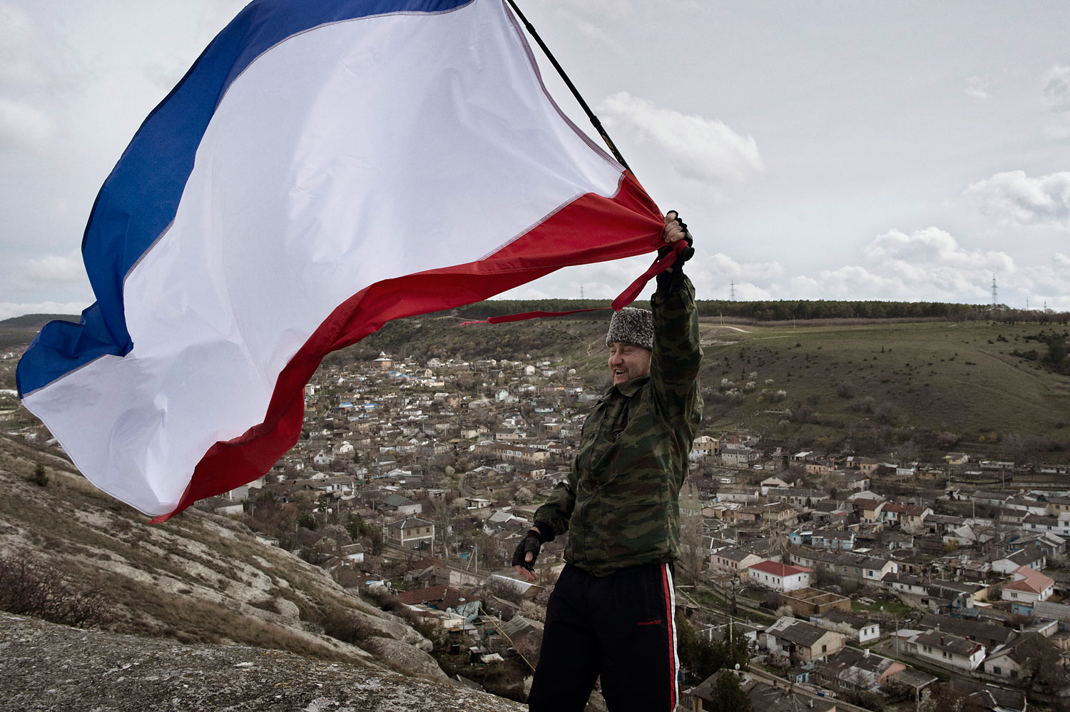 Sergei Yurchenko, the leader of a pro-Russian paramilitary force waves a Crimean flag on a lookout point over his hometown Bakhchysarai, on March 16, 2014.