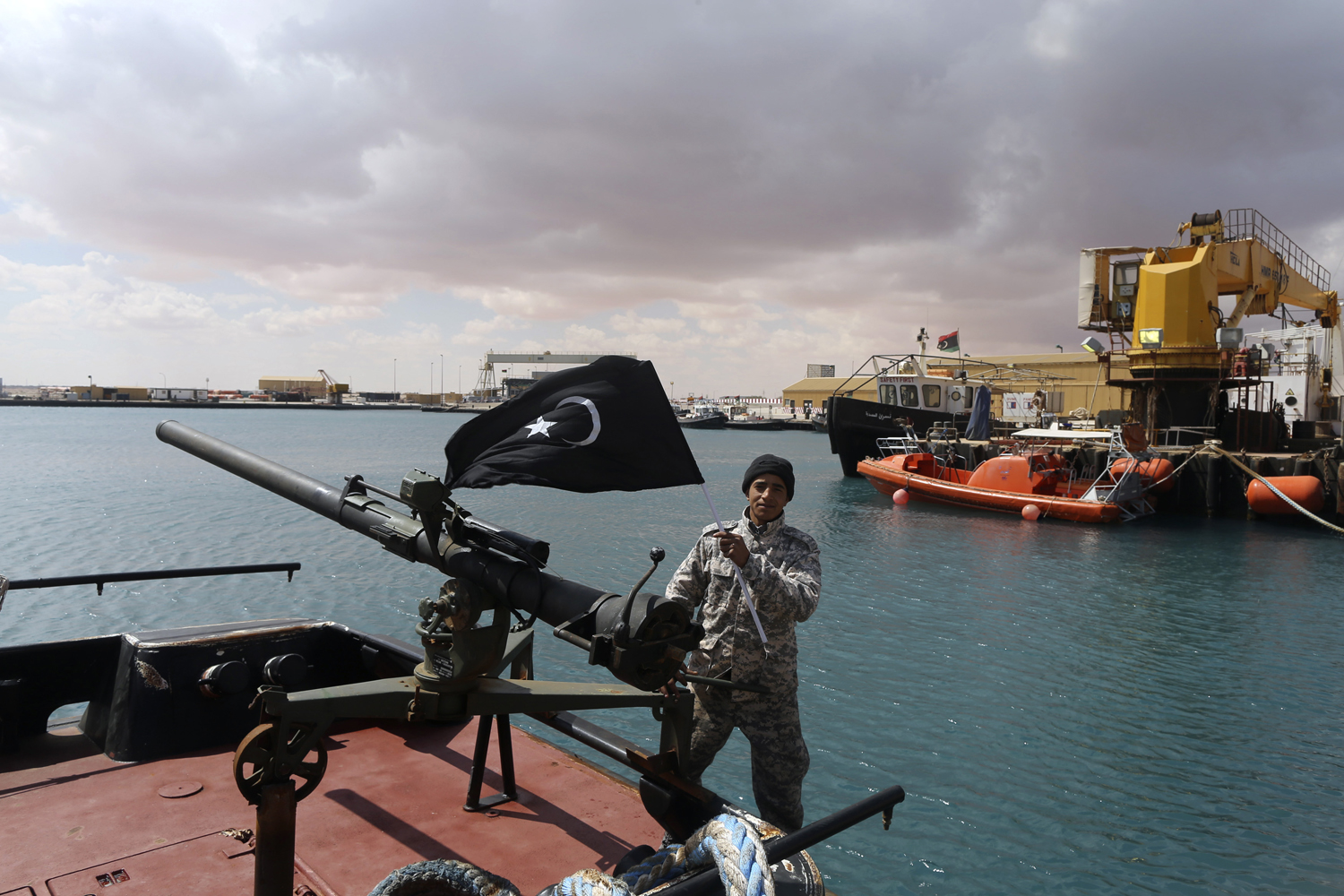 A rebel under Ibrahim Jathran holds the Cyrenaica flag while standing on a boat at Es Sider port in Ras Lanuf