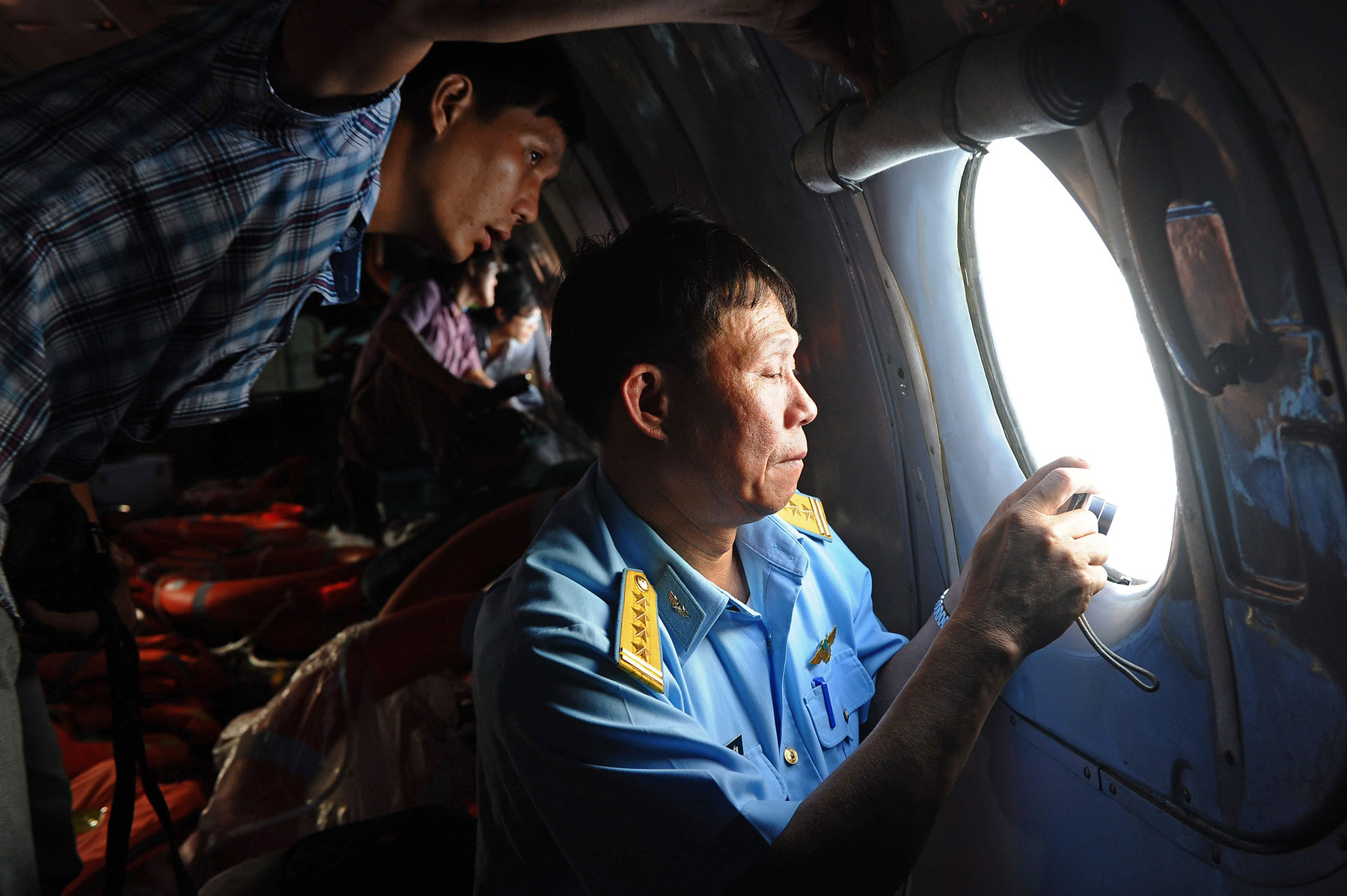 A Vietnamese Air Force officer, right, and a reporter look out the window during search operations over the southern seas off Vietnam on March 9, 2014. (Hoang Dinh Nam&mdash;AFP/Getty Images)