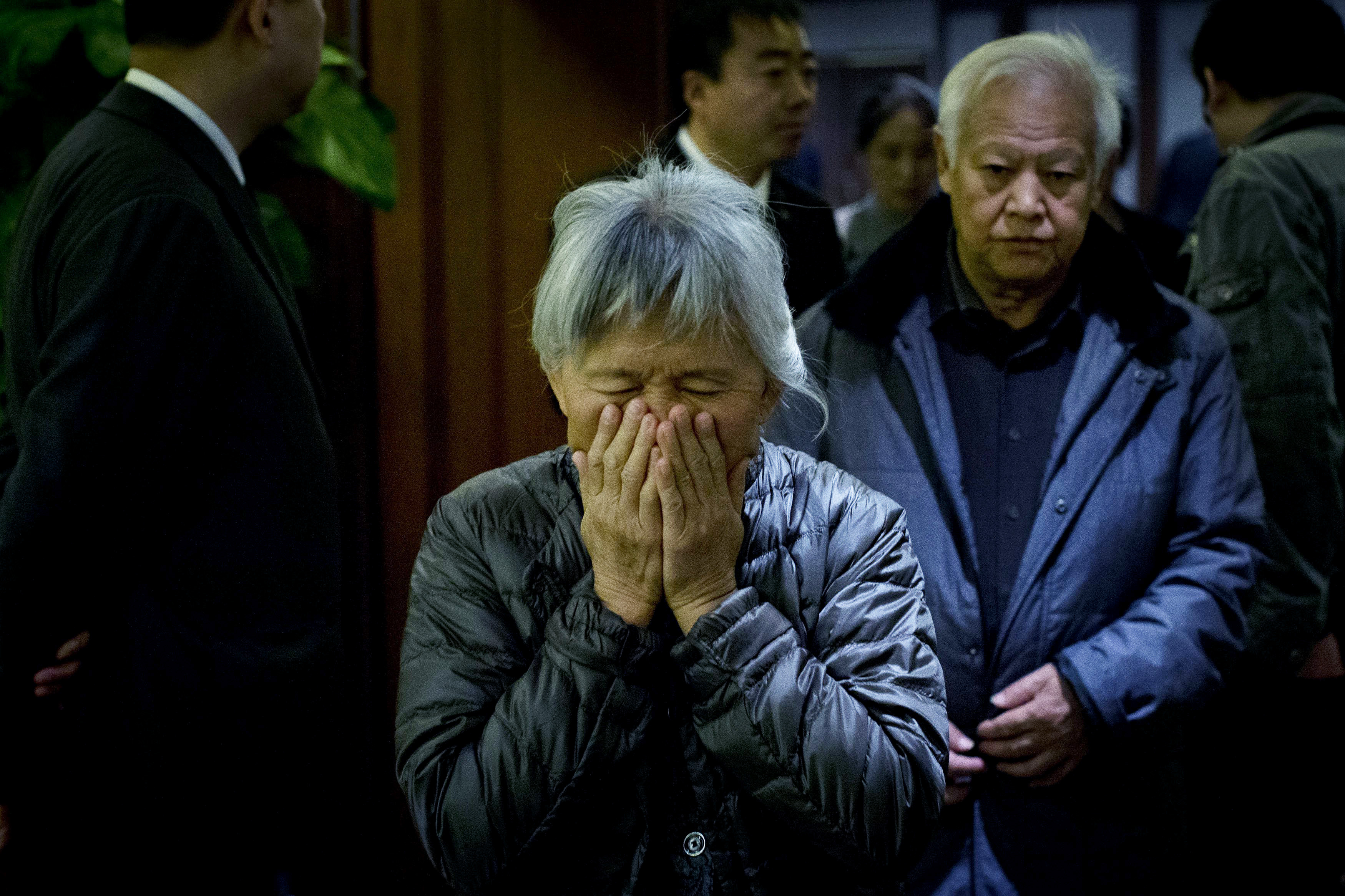 An elderly woman, one of the relatives of Chinese passengers aboard missing Malaysia Airlines Flight MH370, covers her face out of frustration as she leaves a hotel ballroom after a daily briefing meeting with managers of Malaysia Airlines in Beijing, on March 19, 2014. (Alexander F. Yuan—AP)