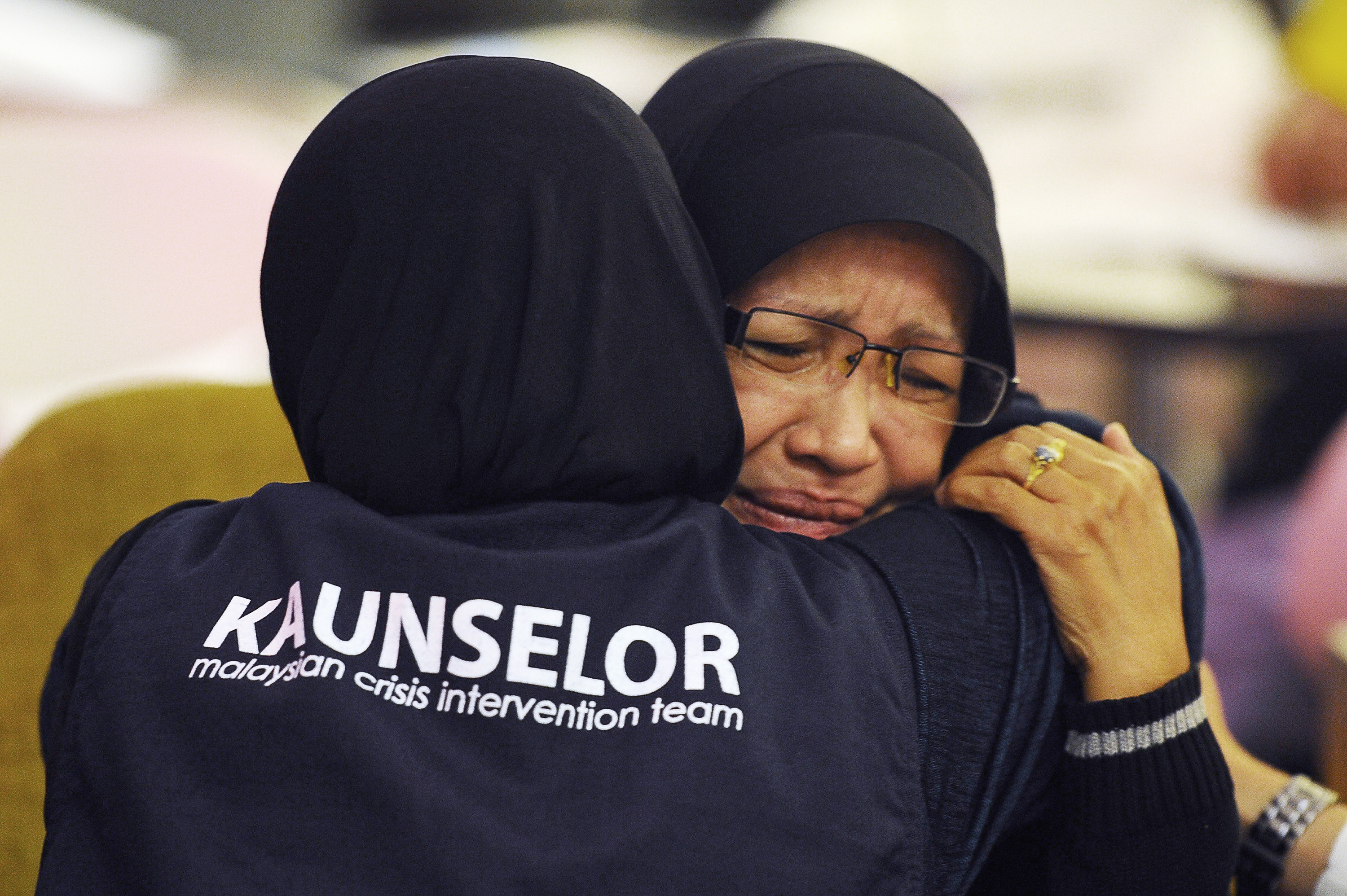 A family member of one of the passengers aboard a missing plane is consoled by a crisis counselor at a hotel in Putrjaya, outside Kuala Lumpur, on March 9, 2014.