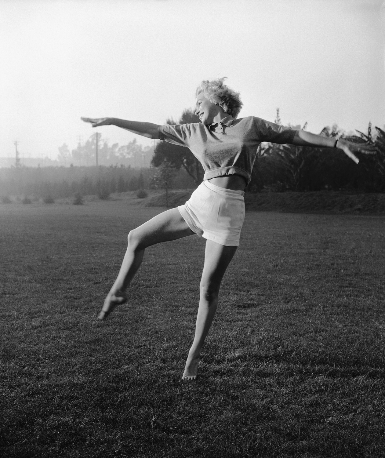 In bare feet, Monroe plays in a grassy field, circa 1955.
