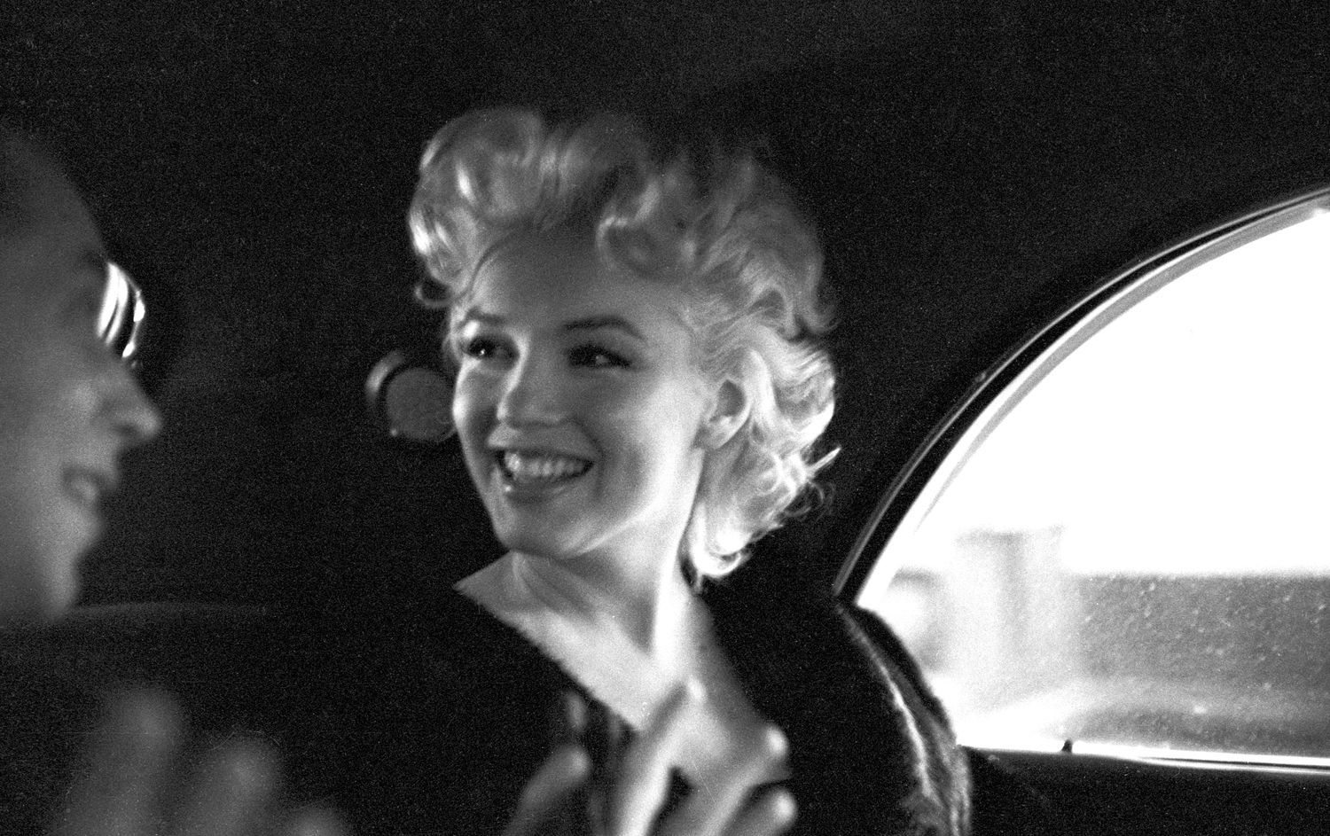 Actress Marilyn Monroe rides in the back of a car with Dick Shepherd on March 30, 1955 in New York City.