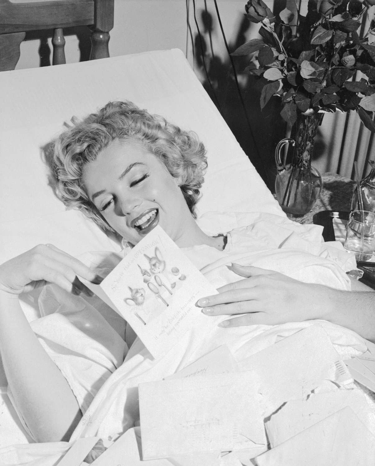 A cheered-up Monroe reads a get-well card from her then boyfriend, baseball legend Joe DiMaggio, after undergoing an operation in 1952.