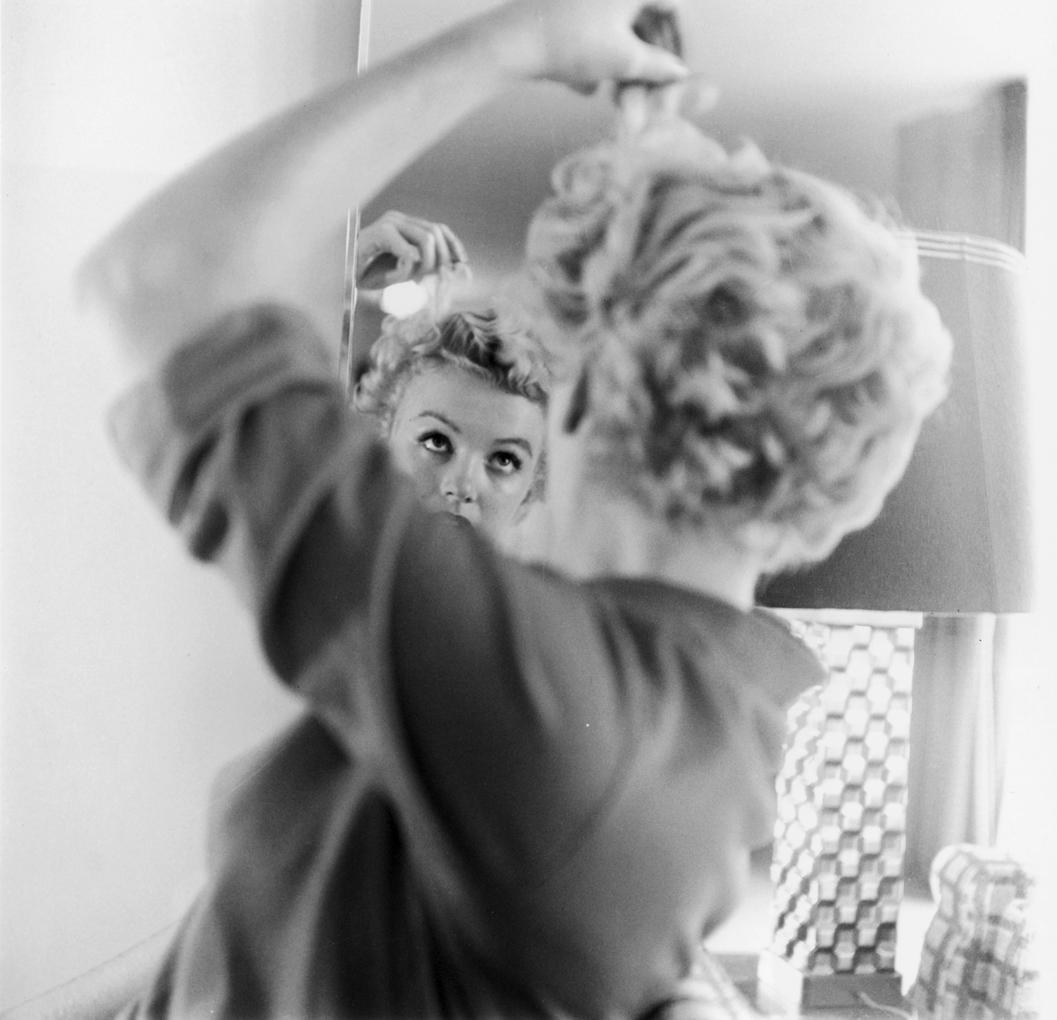 In this undated photo, Monroe touches up her 'do in front of a mirror.