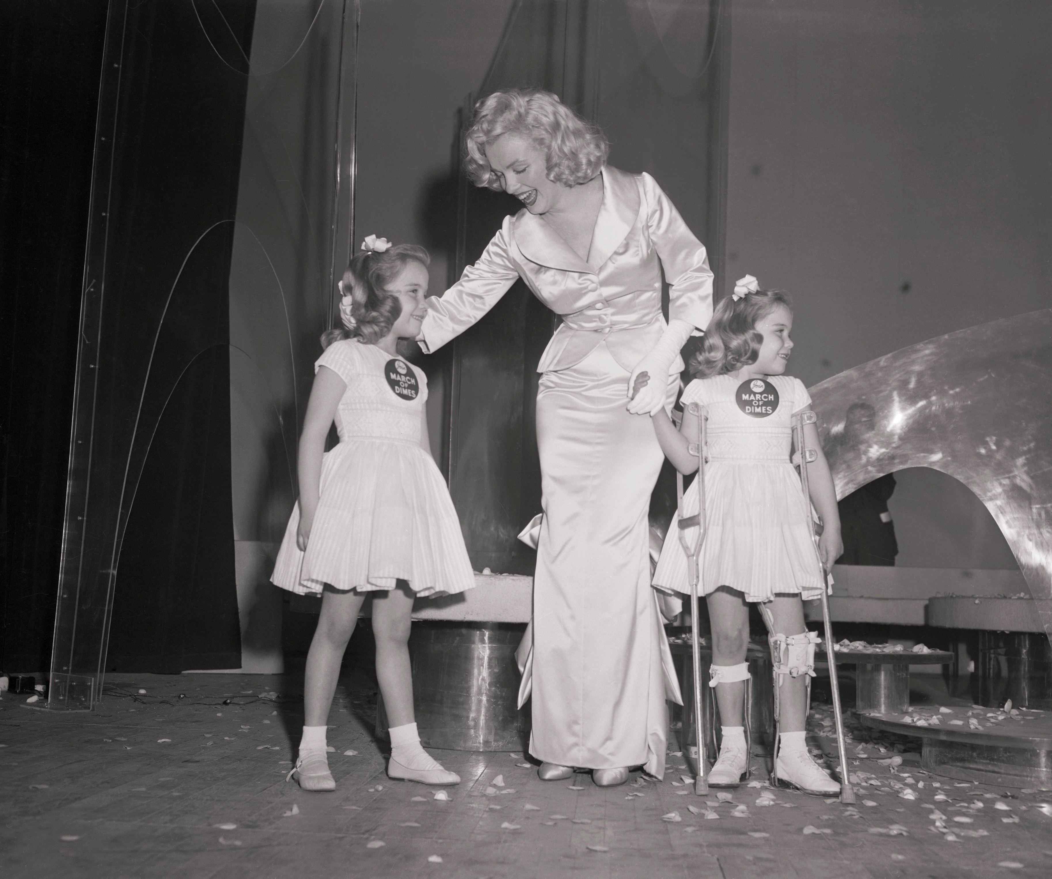 Monroe with twin girls at the March of Dimes fashion show in 1958.