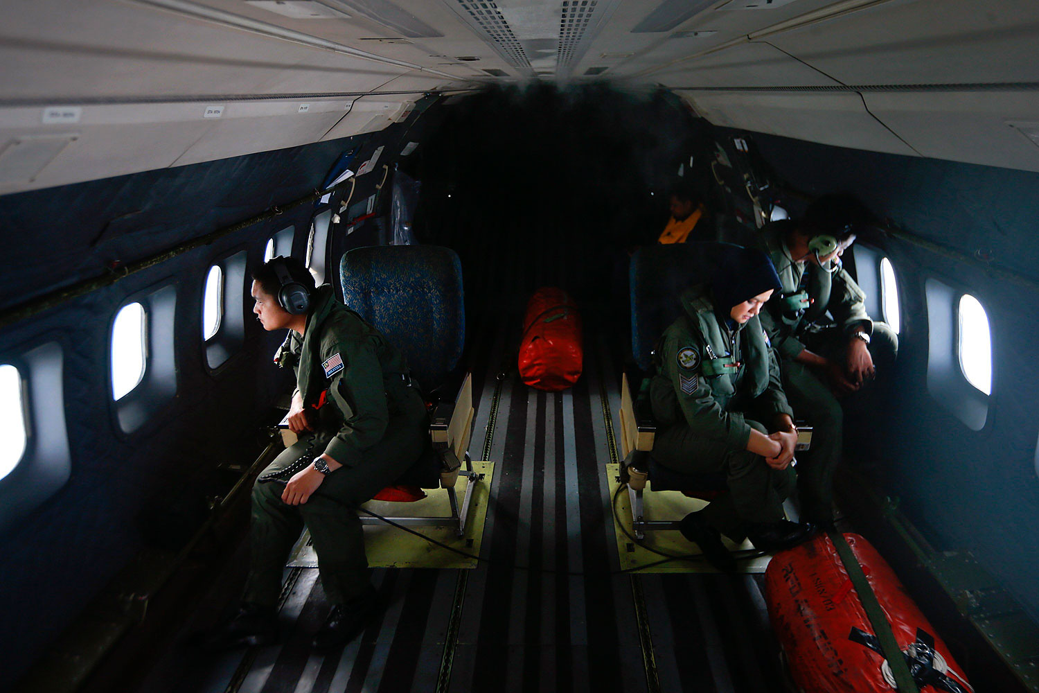 Crew members from the Royal Malaysian Air Force look through windows of a Malaysian Air Force CN235 aircraft during a Search and Rescue  operation to find the missing Malaysia Airlines flight MH370, in the Straits of Malacca, March 13, 2014. 