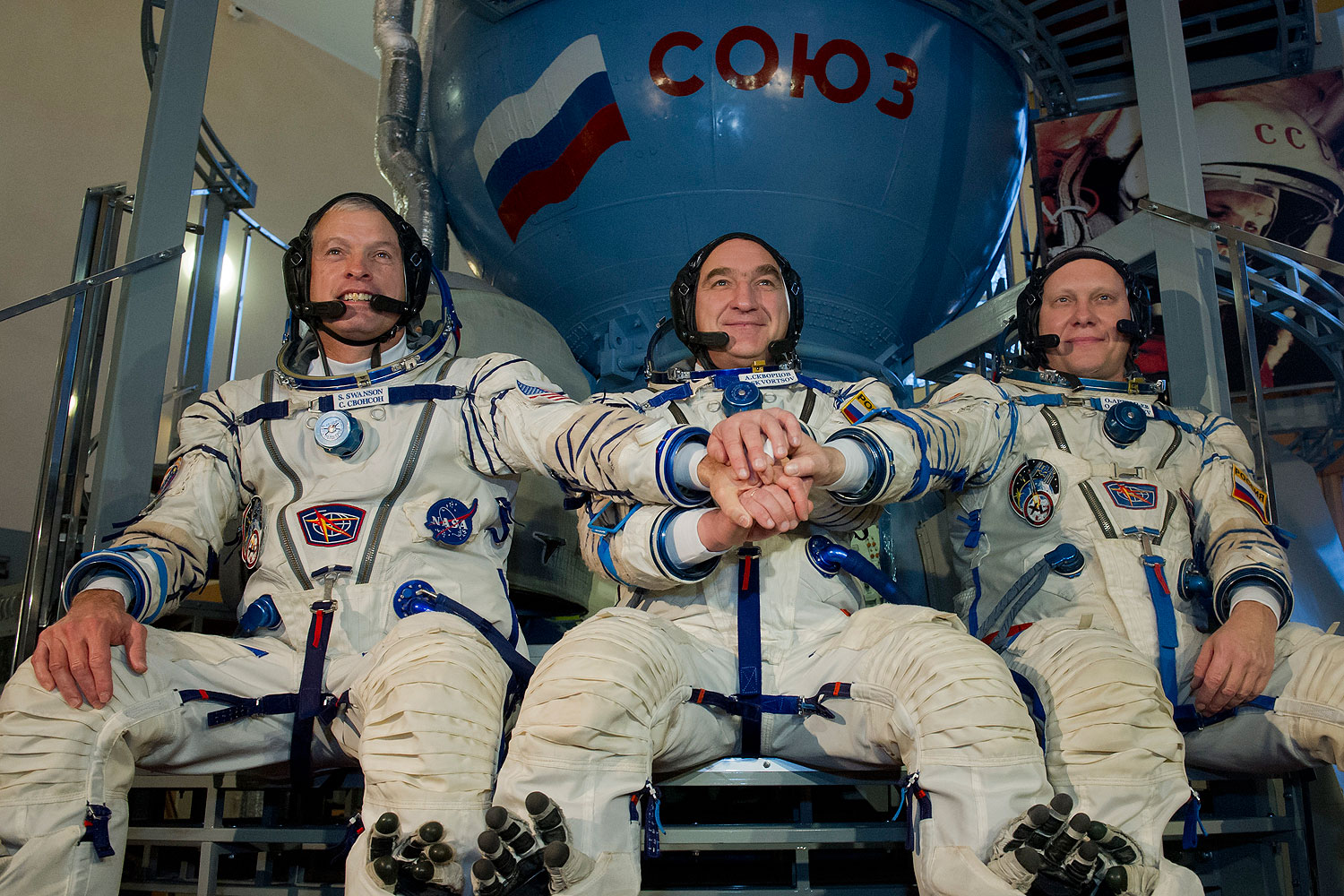 U.S. NASA astronaut Steven Swanson (L) joins hands with Russian cosmonauts, Alexander Skvortsov (C) and Oleg Artemyev (R), in front of a mock-up of a Soyuz TMA spacecraft at the Gagarin Cosmonauts' Training Centre in Star City centre outside Moscow, on March 5, 2014 (AFP / Getty Images)