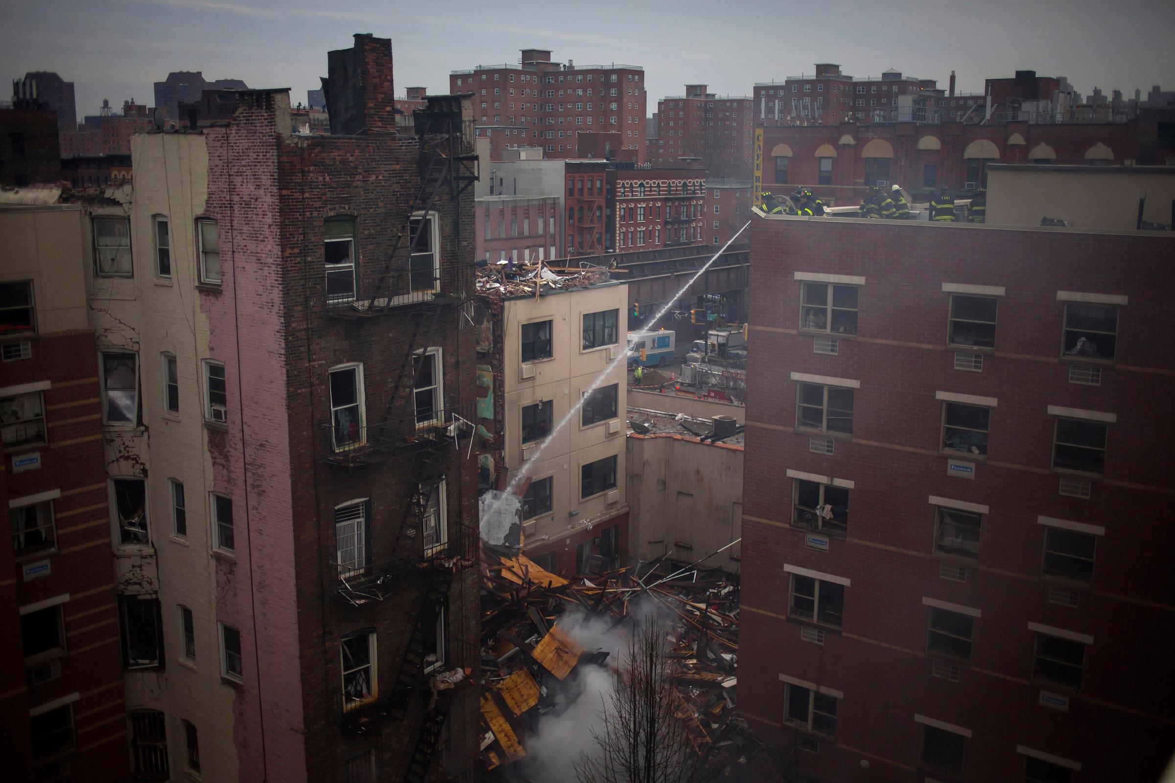 New York City firefighters examine the rubble at an apparent building explosion fire and collapse in the Harlem section of New York