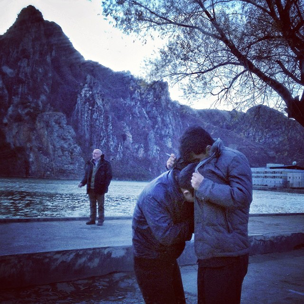 Men shielding themselves from the wind as they try to light their cigarettes, Sinpyong, North Korea, November 11, 2013.