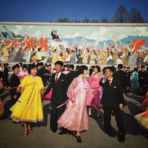 North Koreans dance a traditional folk dance together beneath a huge mosaic of the late leader Kim Il Sung in Pyongyang, April 11, 2013.