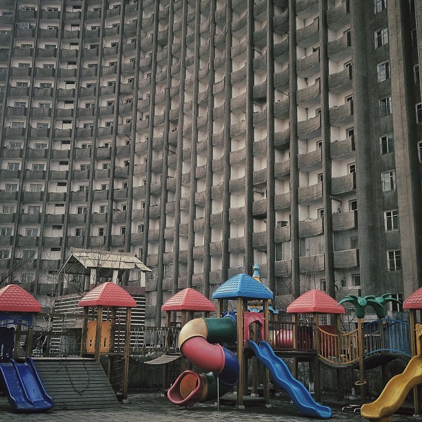 An apartment block stands above the schoolyard playground equipment of a Pyongyang kindergarten, March 12, 2013.