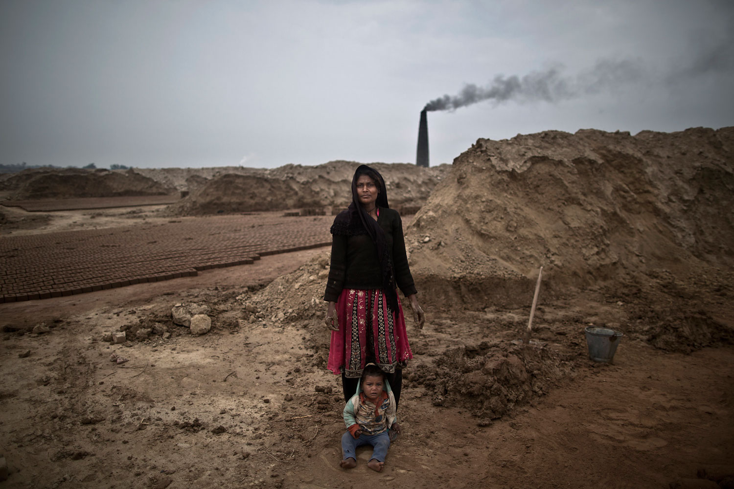 Rubina Rafaqat, 22, a Pakistani brick factory worker, poses for a picture with her child at the site of her work in Mandra, near Rawalpindi, Pakistan, March 3, 2014. Rubina and her husband are in debt to their employer the amount of 200,000 rupees (approximately $2000).