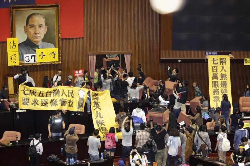 Students and protesters hold banners and chairs inside Taiwan's legislature in Taipei