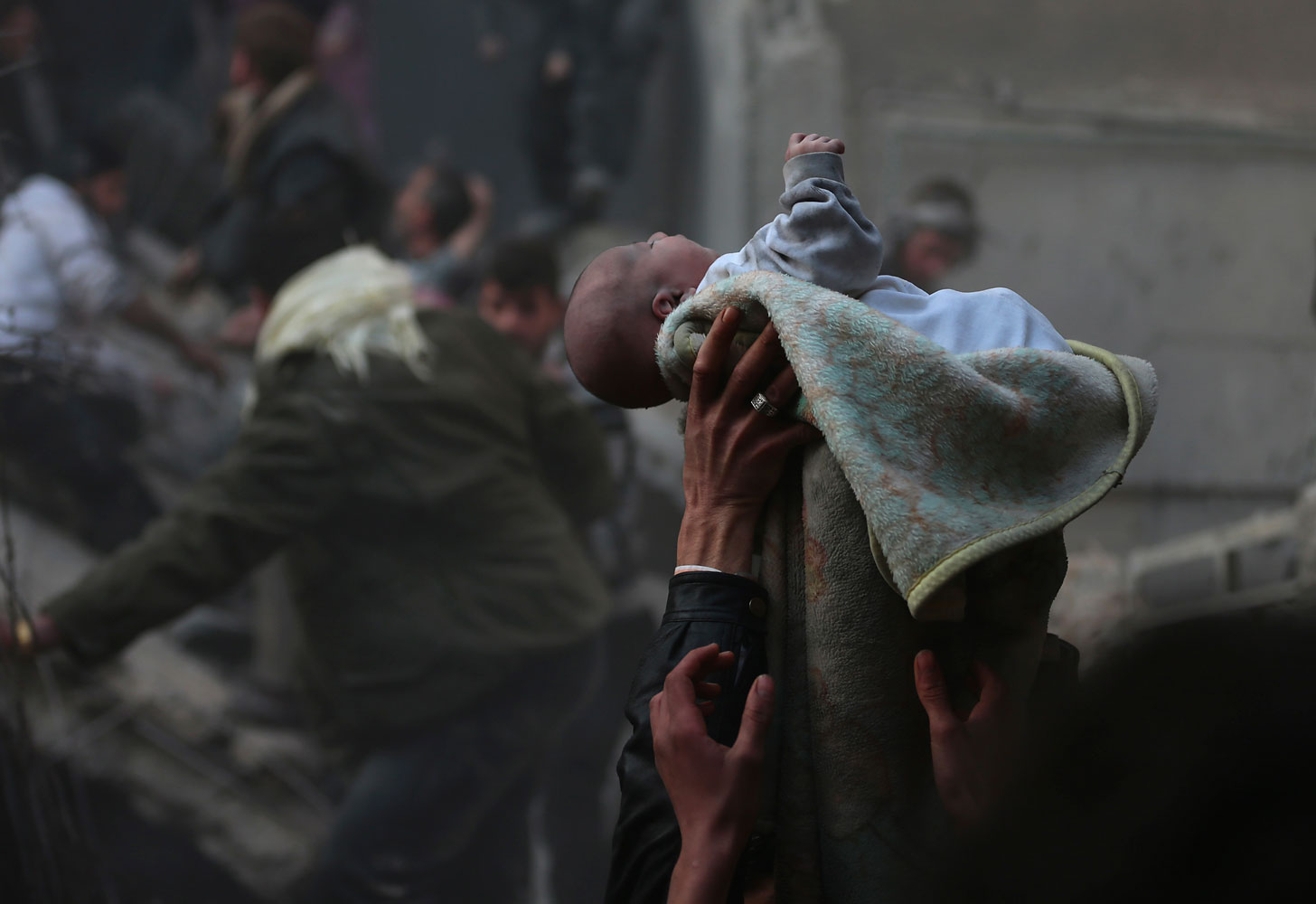 Men hold up a baby saved from under rubble, who survived what activists say was an airstrike by forces loyal to Syrian President Bashar al-Assad in the Duma neighbourhood of Damascus, Jan. 7, 2014. (Bassam Khabieh—Reuters)