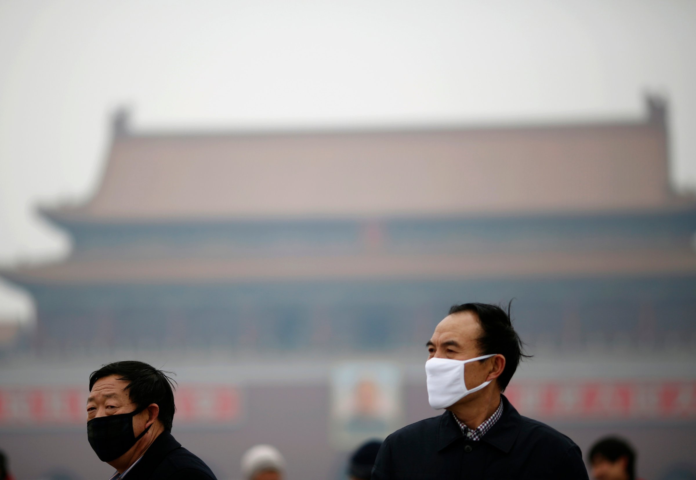 People wearing masks are seen on a hazy day at Tiananmen Square in Beijing