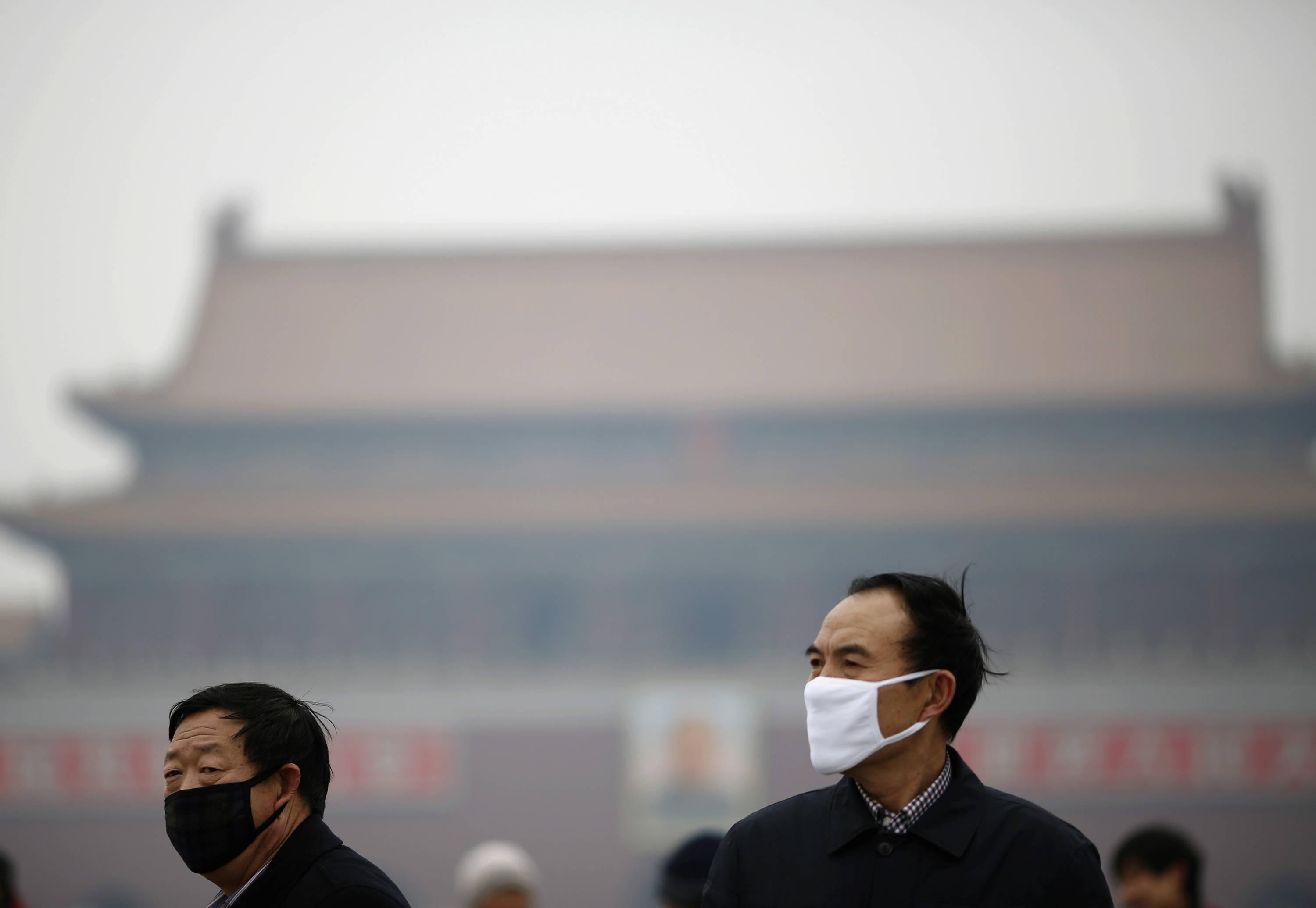 People wearing masks are seen on a hazy day at Tiananmen Square in Beijing