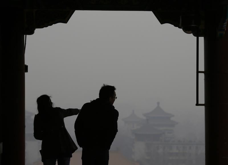 Visitors are silhouetted against thick smog on the top of Jingshan Park near the Forbidden City in Beijing