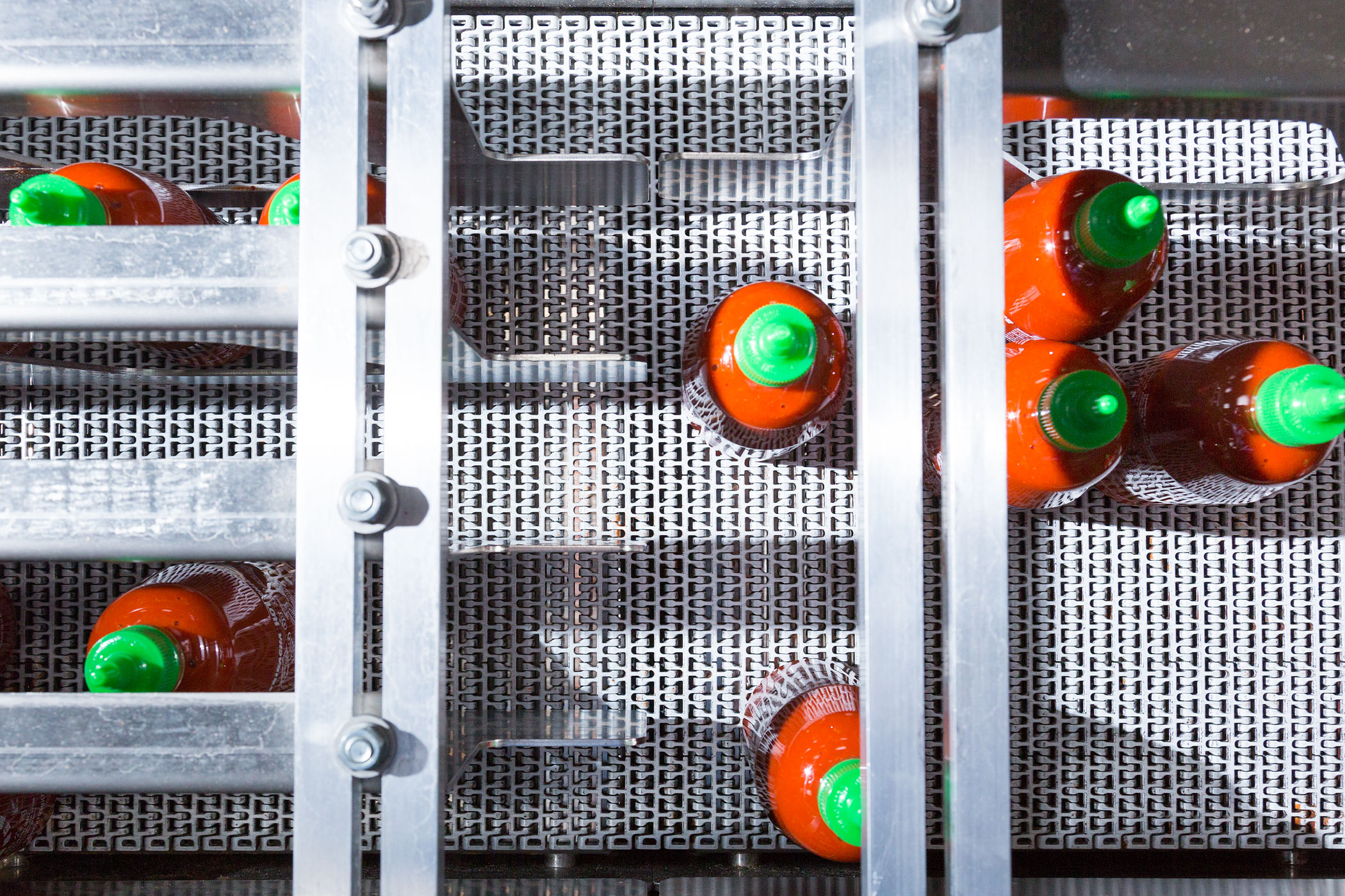 Filled and capped bottles of Sriracha come off the assembly line and are organized for boxing.