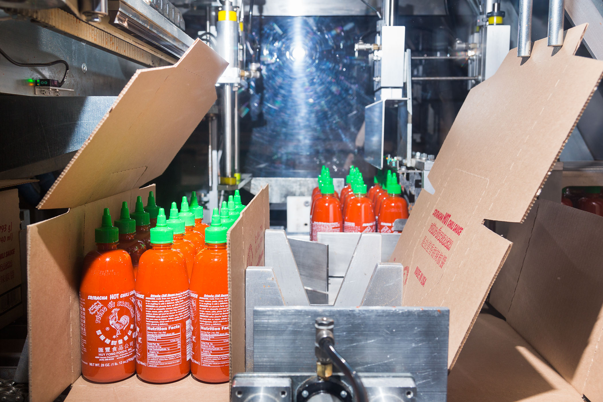 A machine boxes Sriracha for shipping.