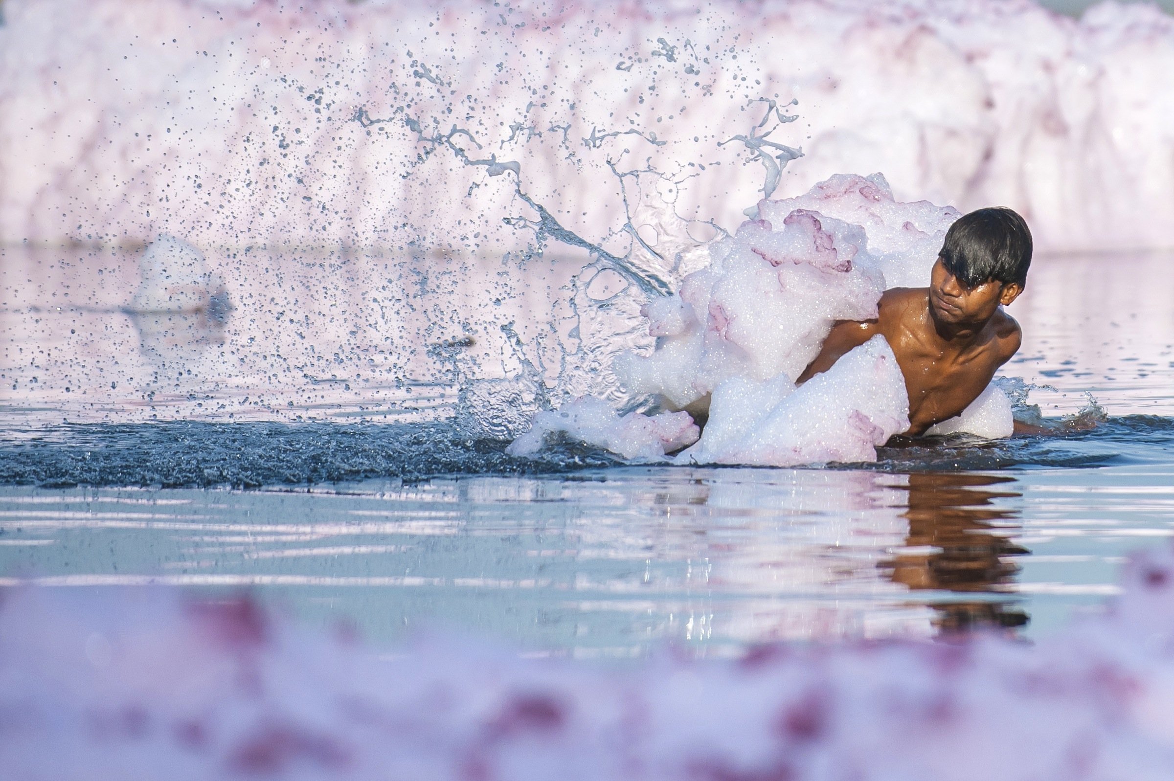 A man tries to get rid of a thick layer of flowing foam as he takes a bath in river Yamuna on March 19, 2014 in New Delhi. Yamuna is the largest tributary of the holy river, Ganges, and has often been described as the most polluted water body in northern India. The extreme pollution levels cause deposition of foam on the top surface of the river.