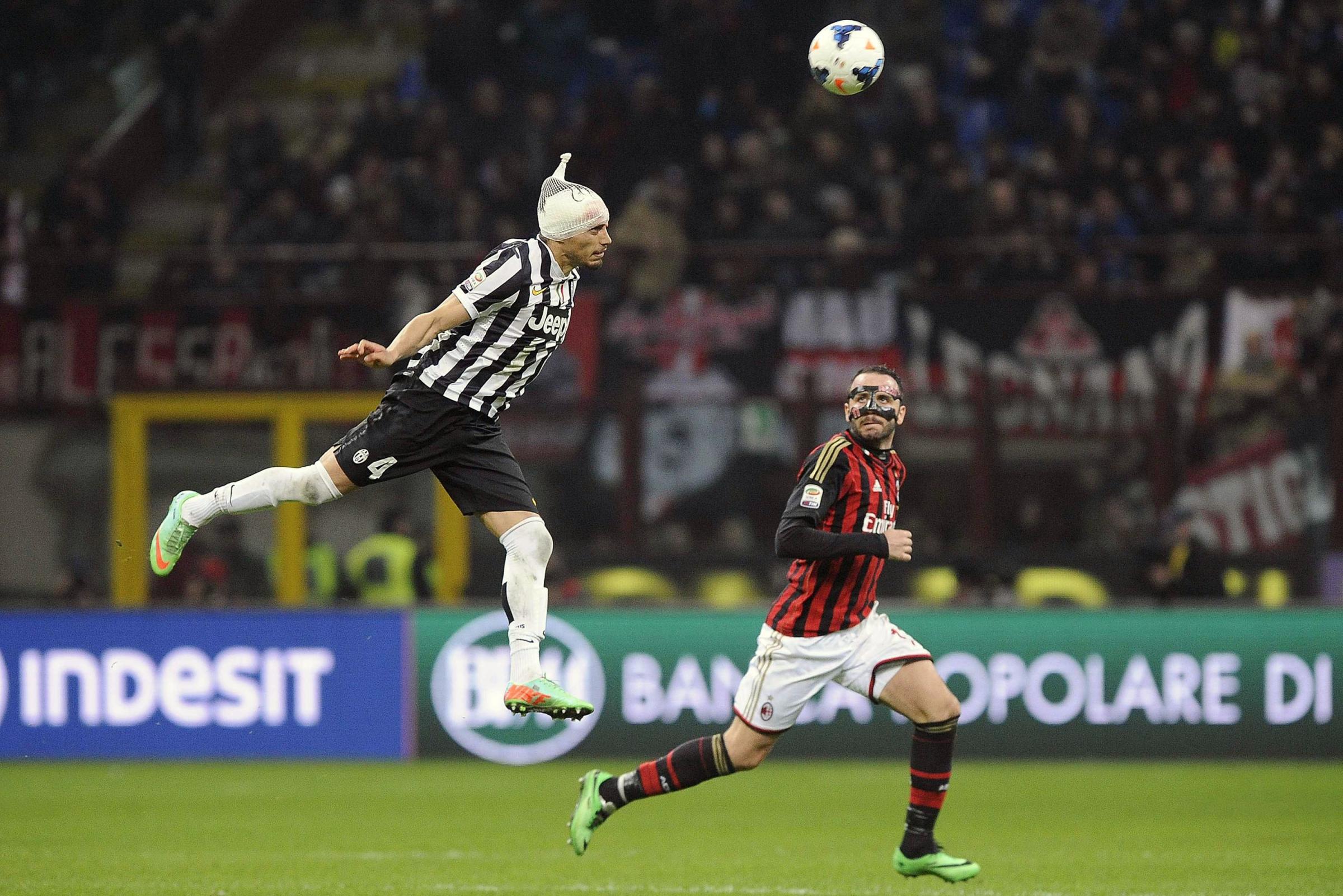 Juventus' Martin Caceres, left, jumps for the ball as AC Milan's Giampaolo Pazzini looks at him during their Italian Serie A soccer match at the San Siro stadium in Milan March 2, 2014.