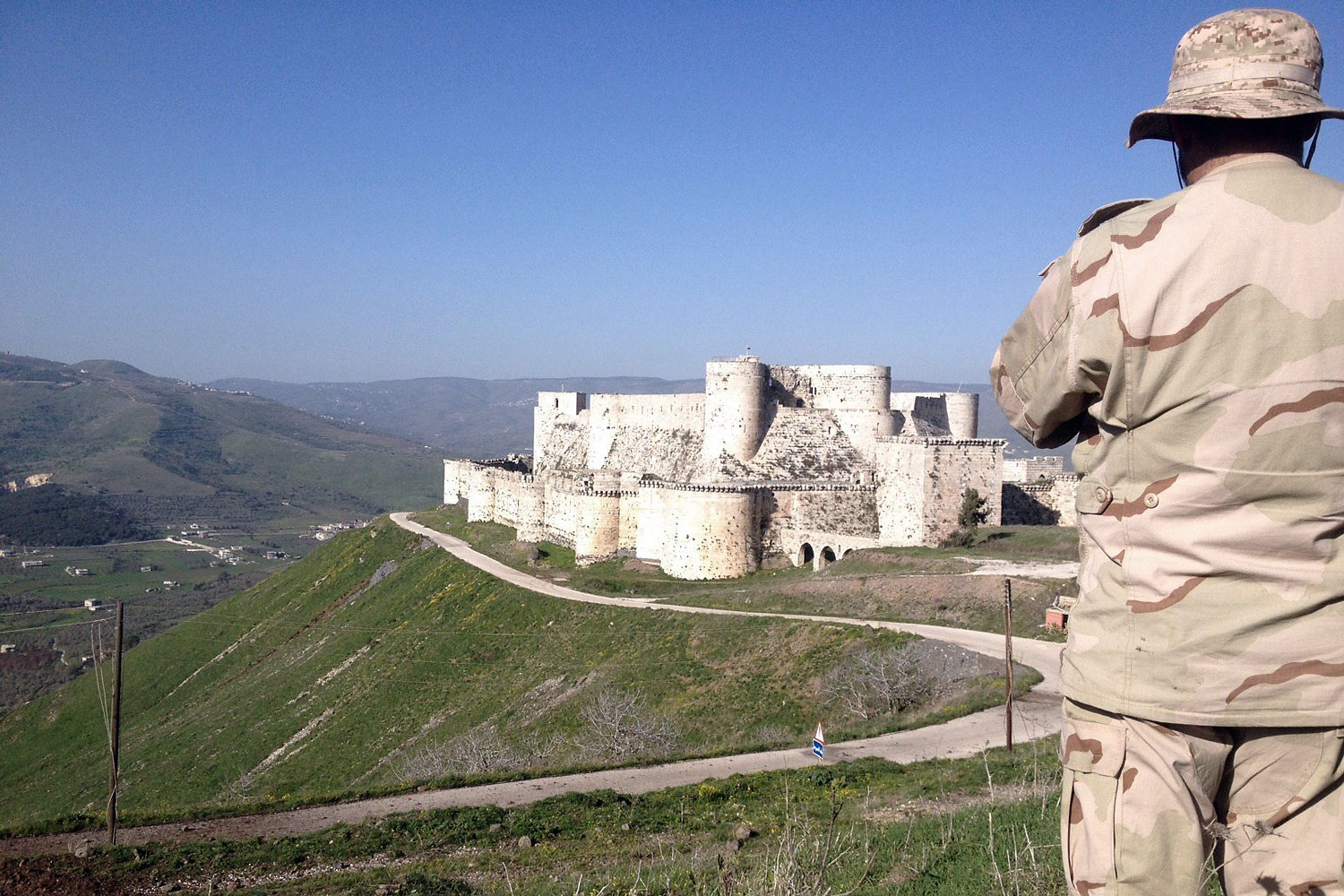 A government soldier looks out over the renowned Crusader castle Krak des Chevaliers near the Syria-Lebanon border after forces loyal to Syria's President Bashar al-Assad seized the fortress on March 20, 2014.