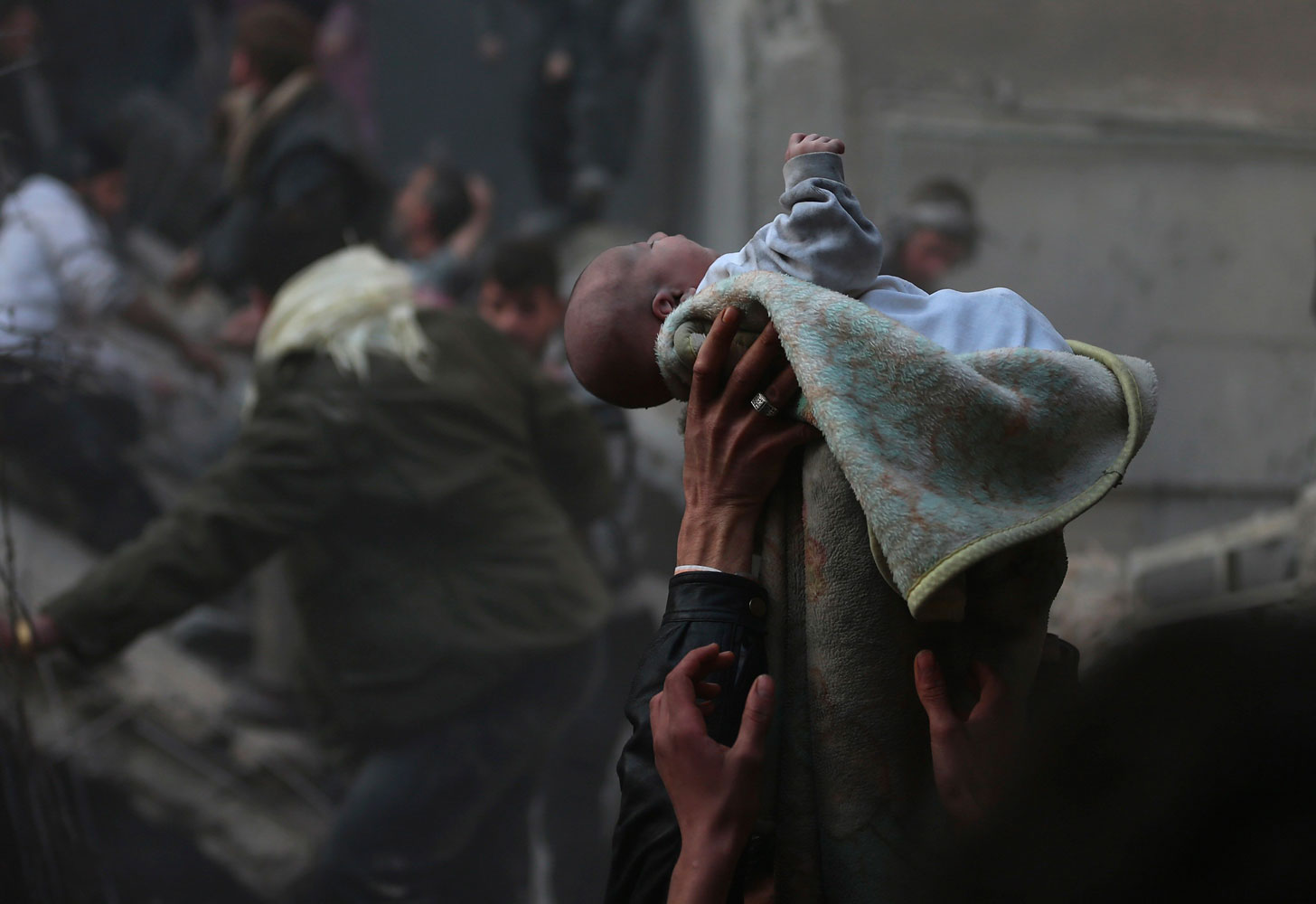 Men hold up a baby saved from what activists say was an airstrike by forces loyal to Syrian President Bashar al-Assad in Damascus on January 7, 2014.