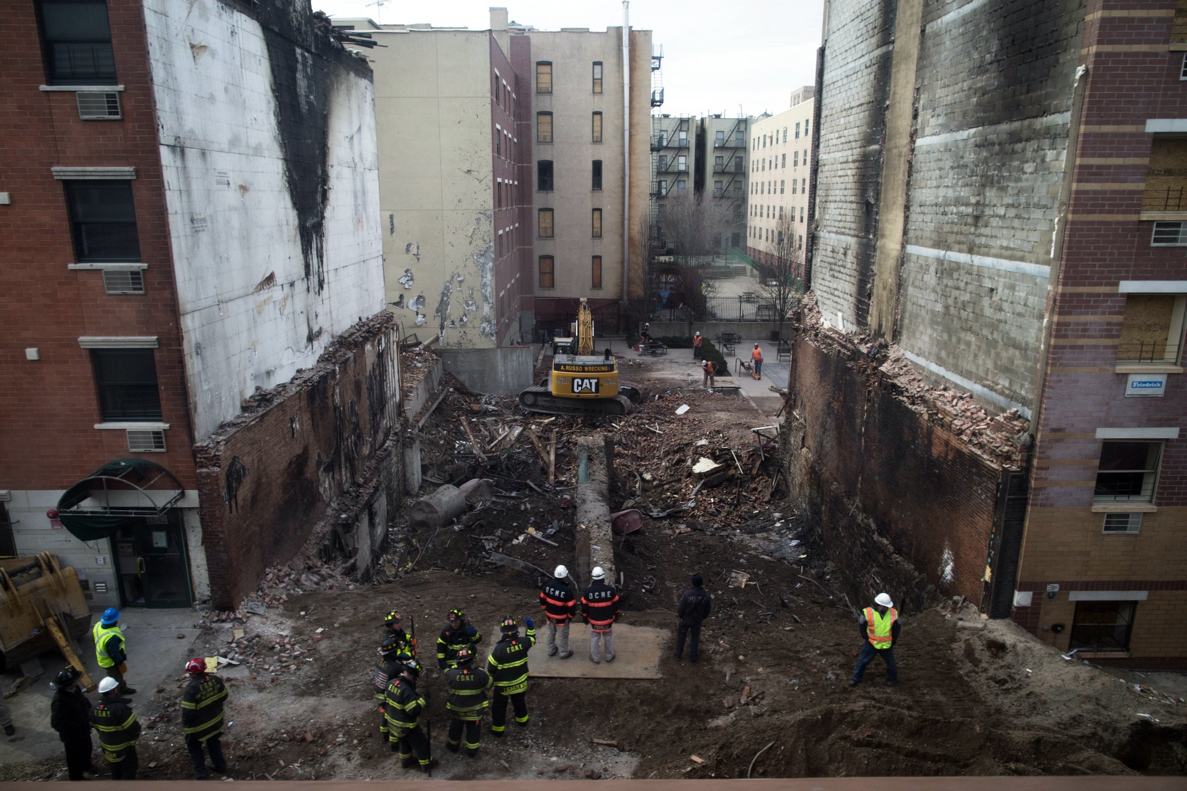 Workers stand beside the recently cleared basement of the two buildings leveled by an explosion on Wednesday in the East Harlem neighborhood of New York