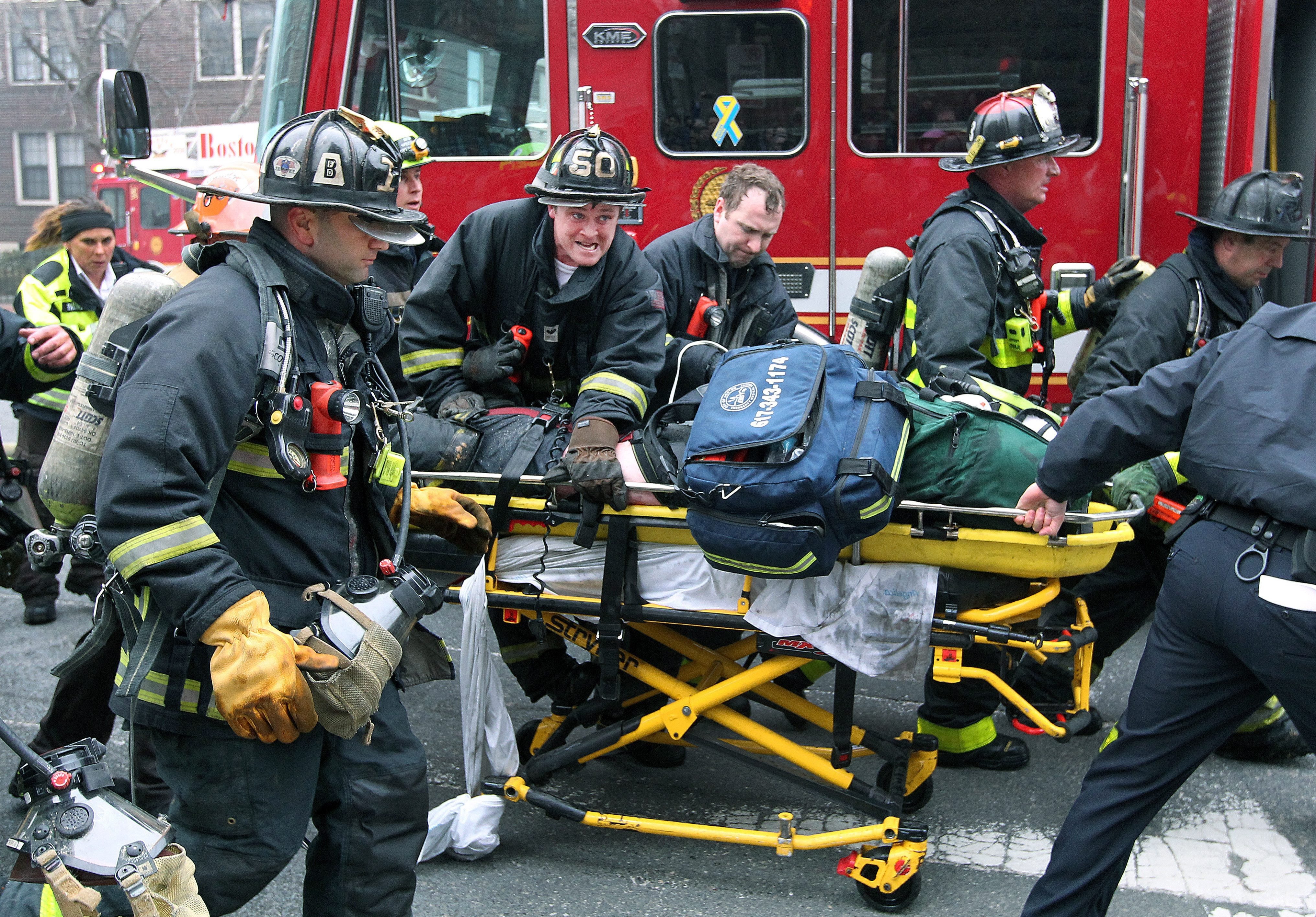 Boston Fire Department firefighters working on a fellow firefighter as he is rushed to an ambulance after being injured during a nine alarm fire in the Back Bay neighborhood of Boston, March 26, 2014.
