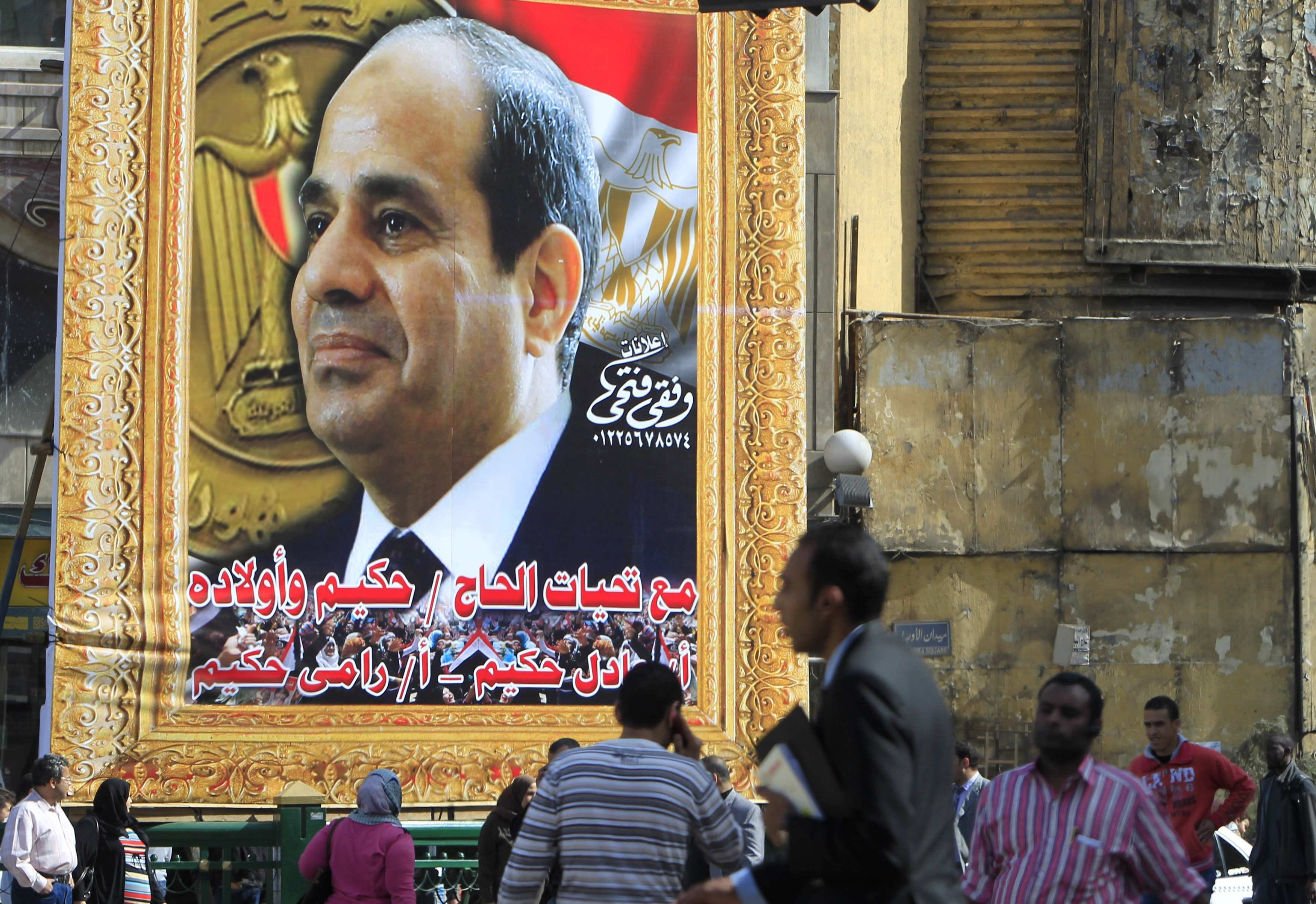 People walk past a banner for Egypt's army chief Field Marshal Abdel Fattah al-Sisi in downtown Cairo March 26, 2014.