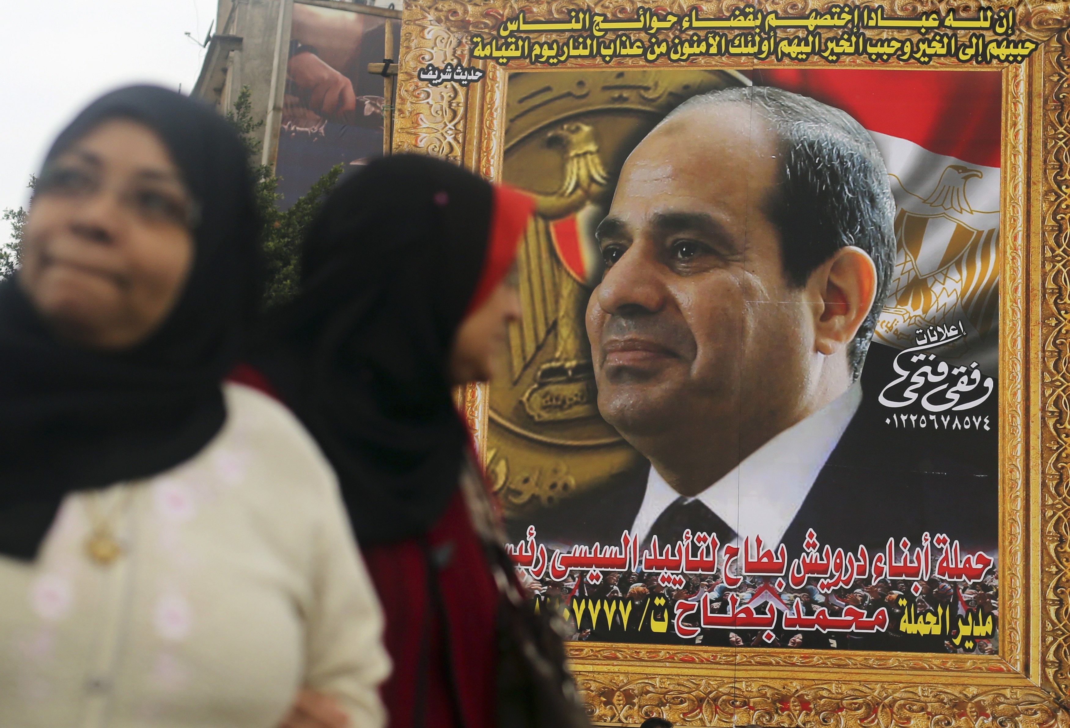 Women walk in front of huge banner for Egypt's army chief, al-Sisi in downtown Cairo
