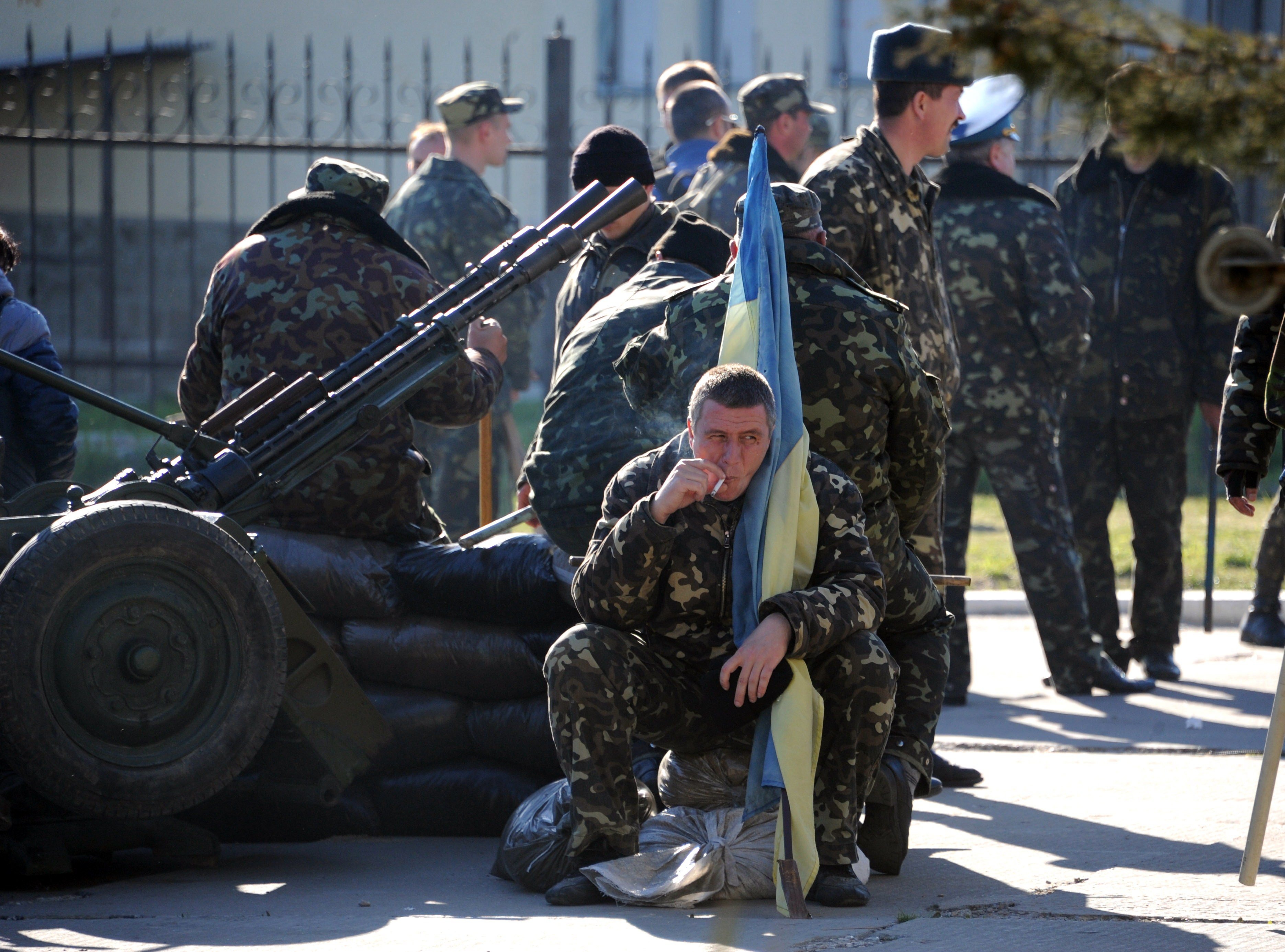 A Ukrainian officer holds his flag as he smokes a cigarette before pro-Russia militia and Russian armed forces backed by armoured vehicles broke inside the Ukrainian airbase in the small city of Belbek near the Crimean city of Sevastopol on March 22, 2014.