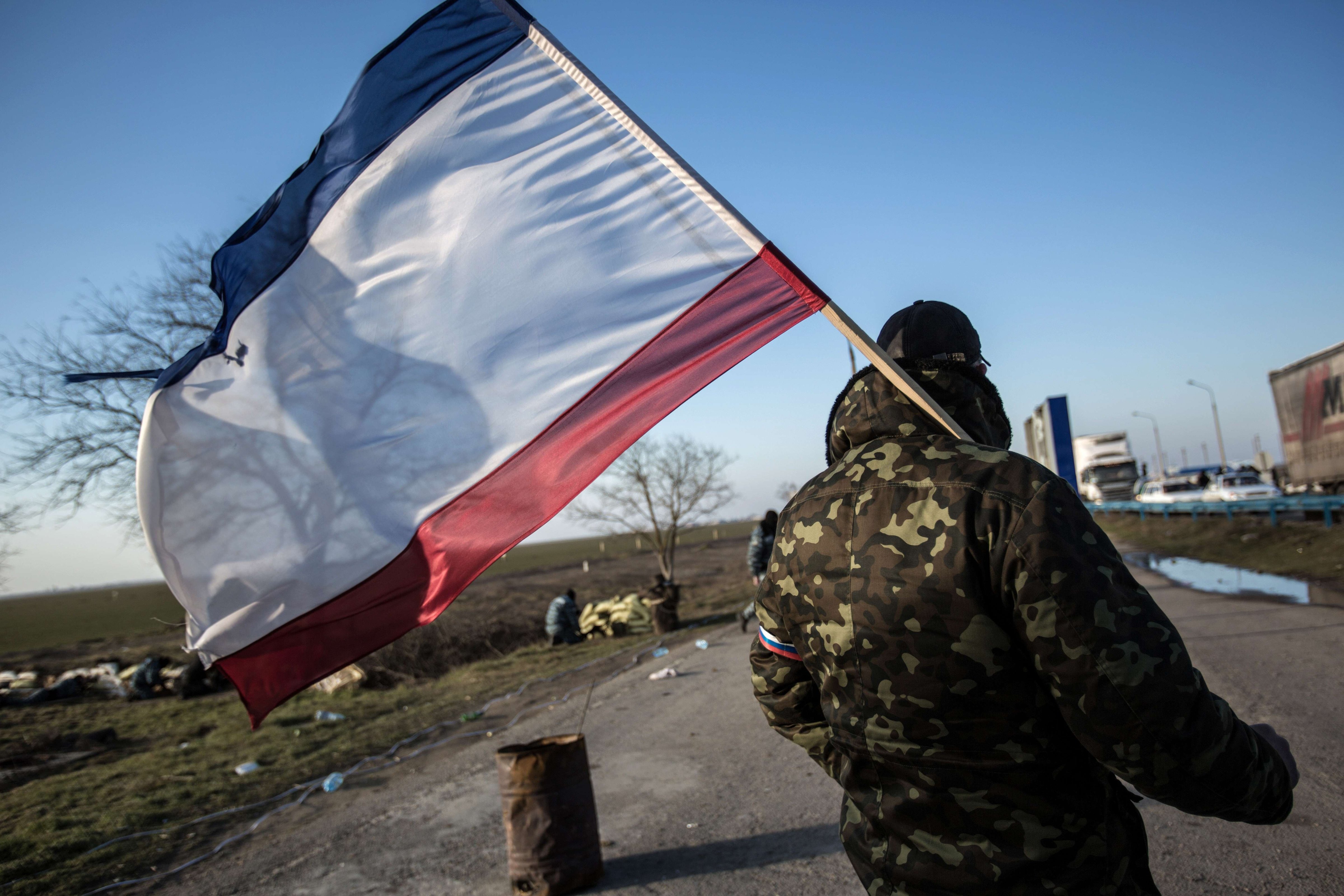 A pro-Russia supporter waves a Crimean flag at Chongar checkpoint blocking the entrance to Crimea